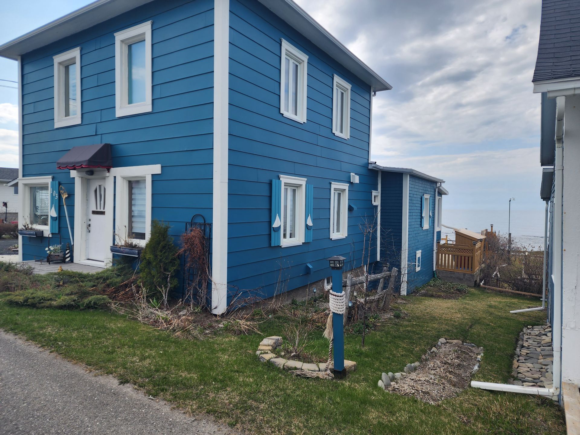 Une maison bleue avec des bordures blanches est à côté d'une maison blanche