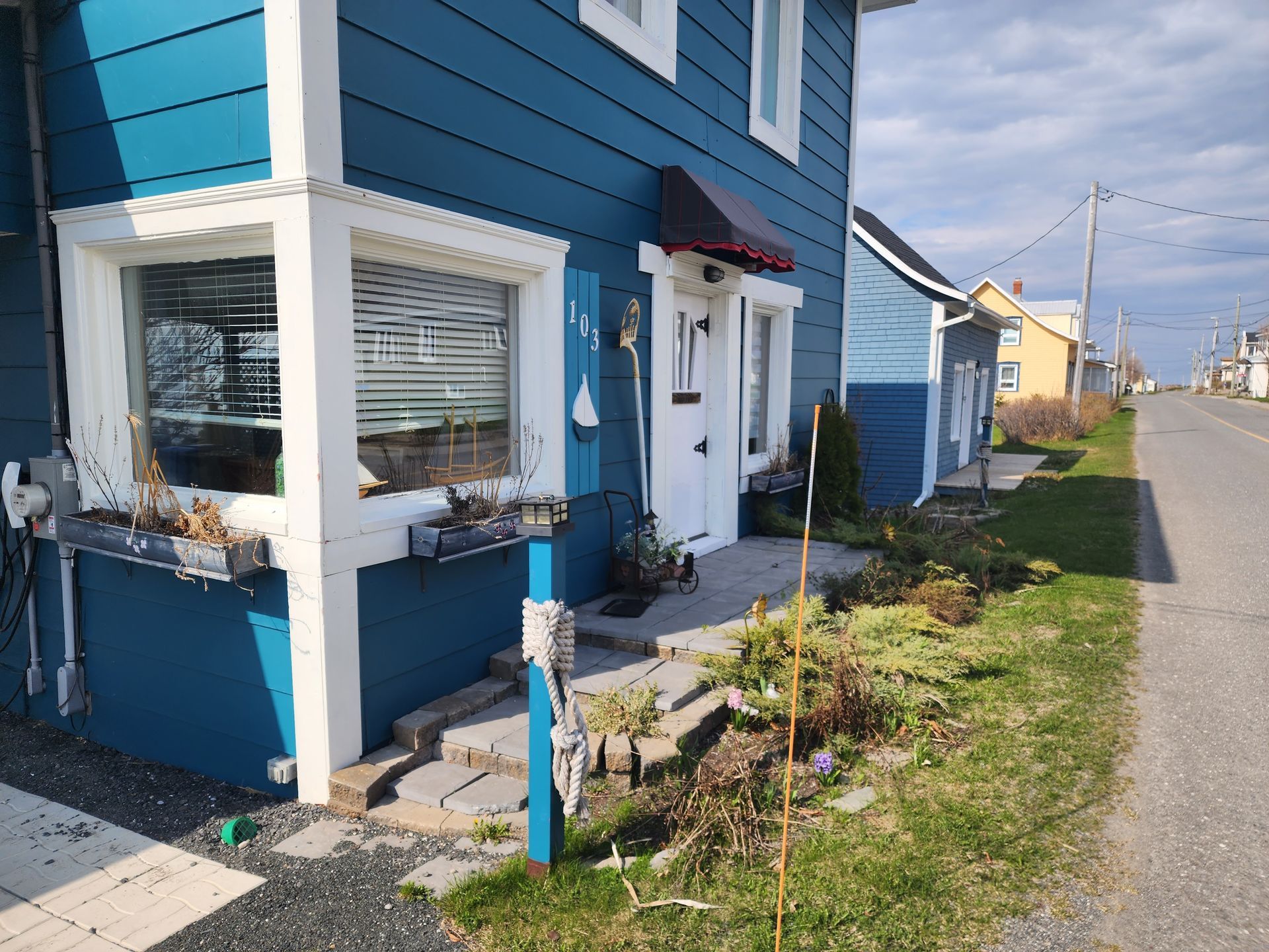 Une maison bleue avec une bordure blanche et un auvent rouge