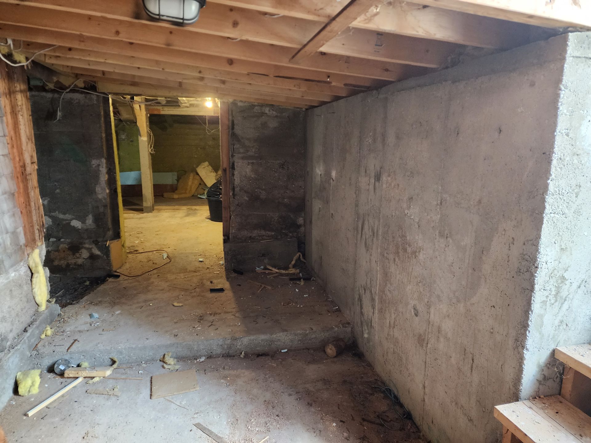 Un sous-sol vide avec un mur en béton et un plafond en bois.
