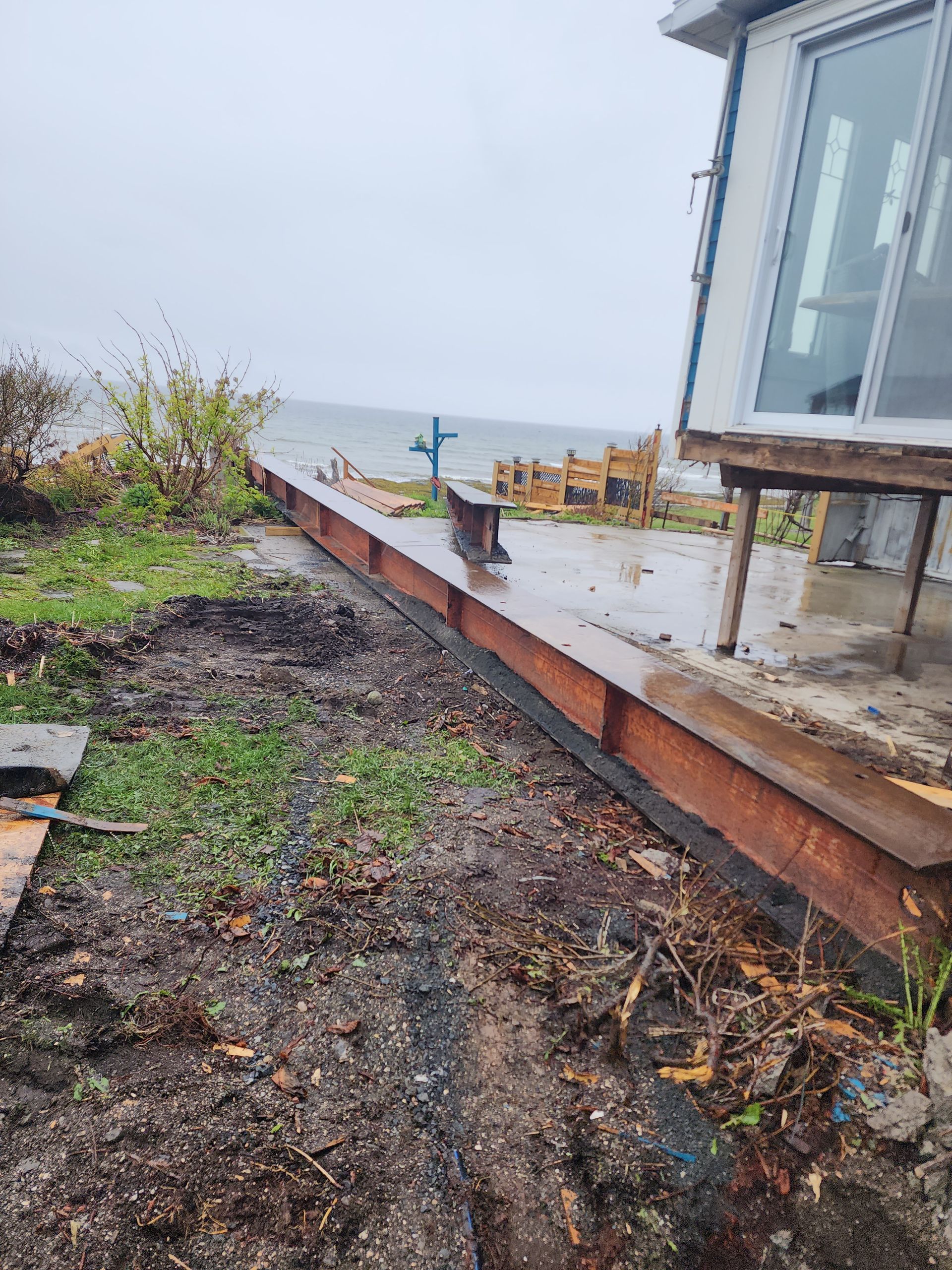 Une maison est située au sommet d'une colline de terre à côté de l'océan.