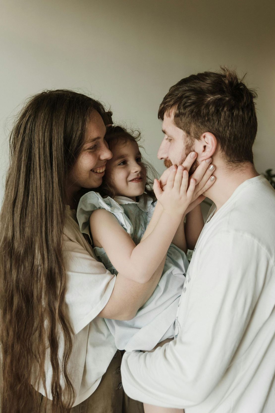 A man and woman are holding a little girl in their arms.