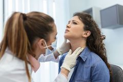 A woman is having her throat examined by a doctor.