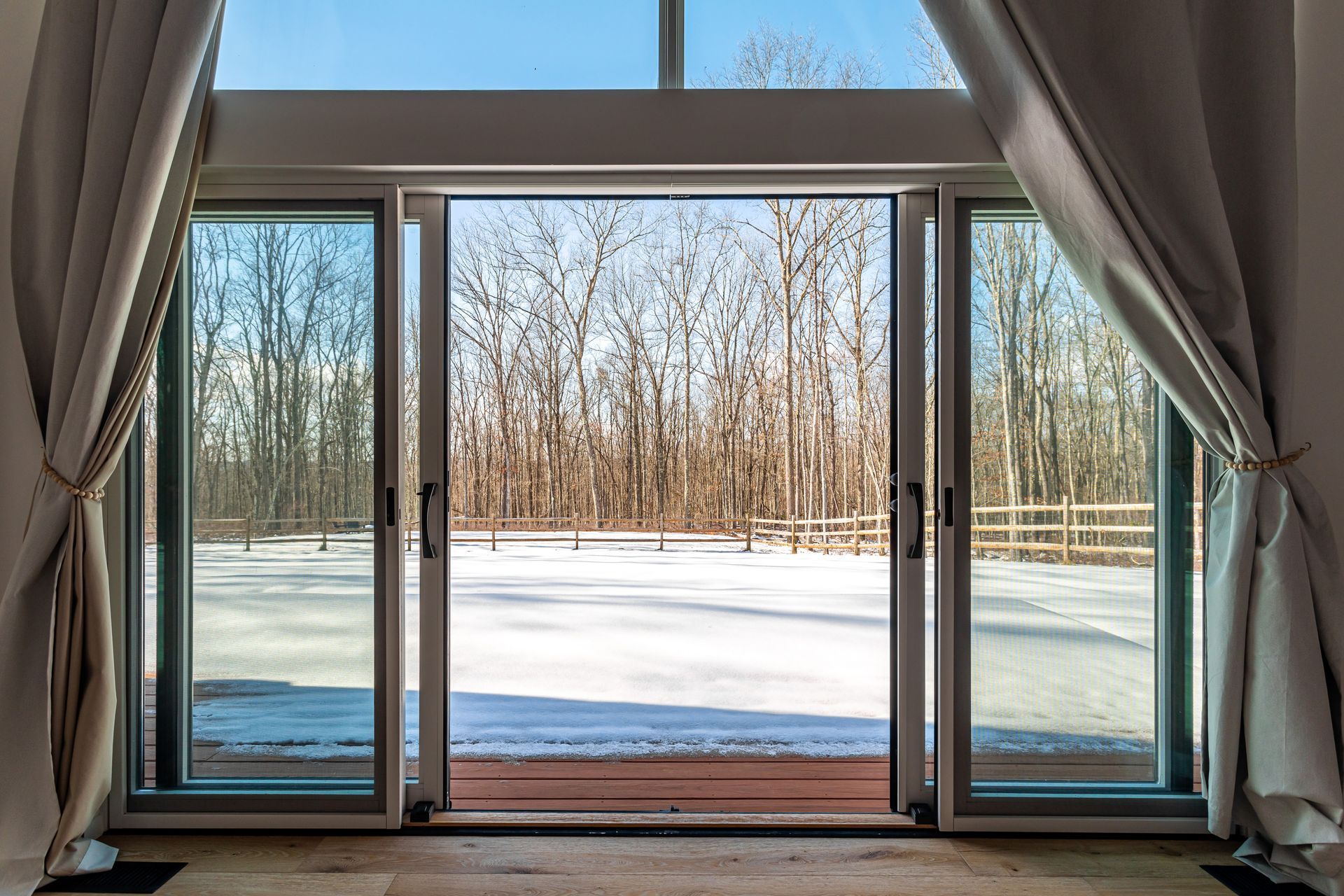 Large sliding glass doors opening to a snowy yard with trees and bright natural light.