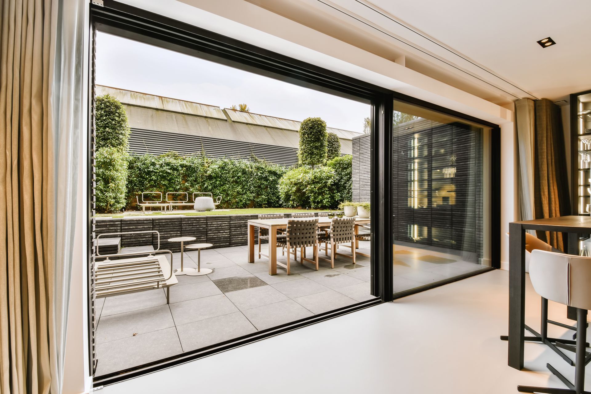 Modern patio with outdoor seating and dining area viewed through large sliding glass doors.