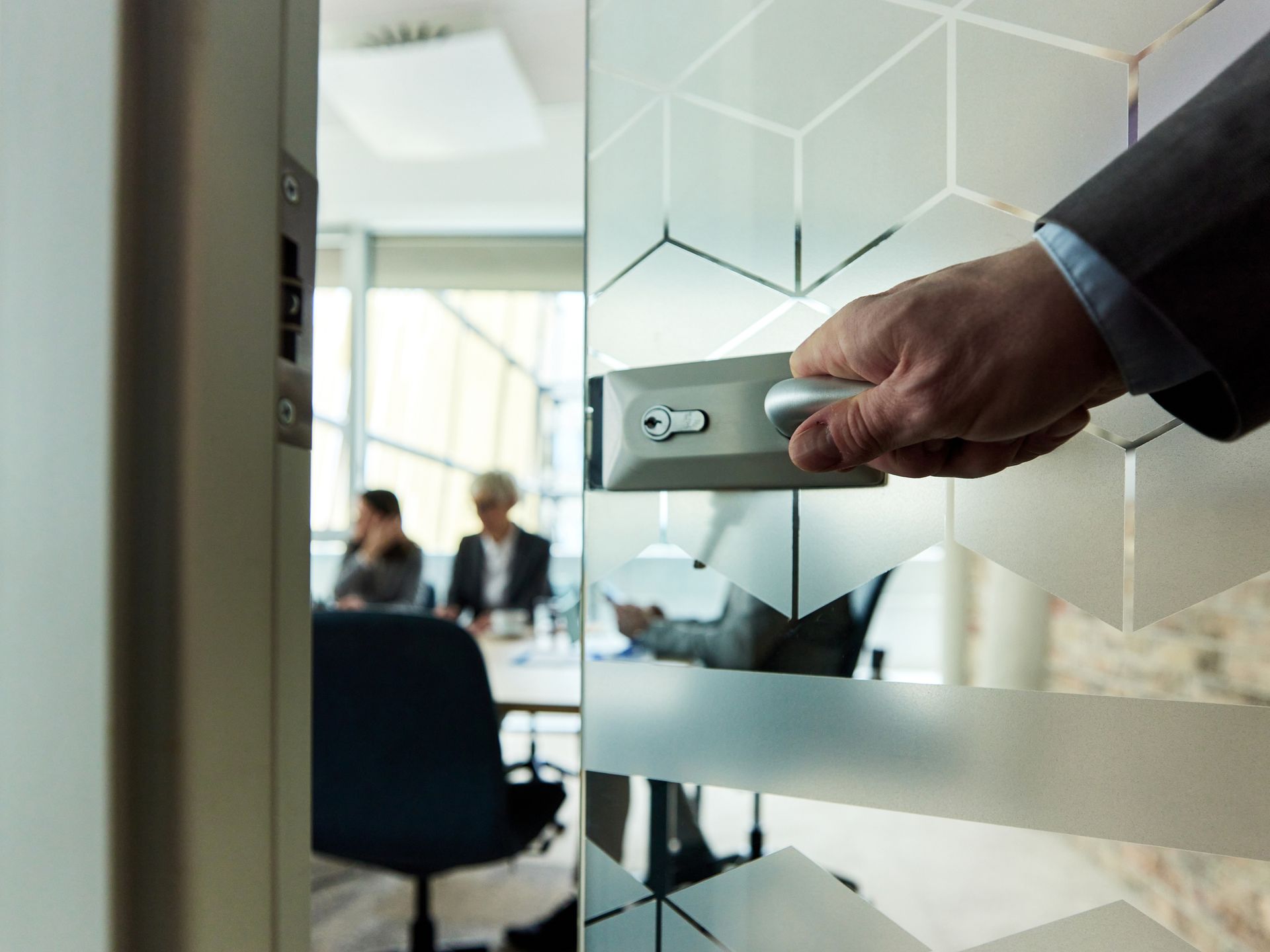 Close-up of the hand of a businessman opening a glass door into a meeting room Close-up of the hand of a businessman opening a glass door into a meeting room