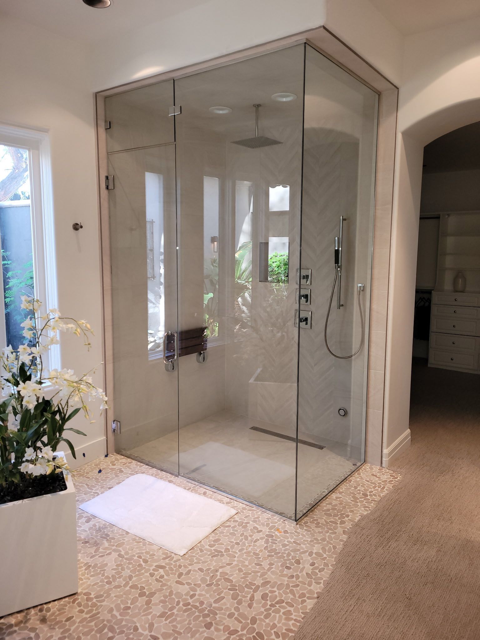 A bathroom with a walk in shower and a window.