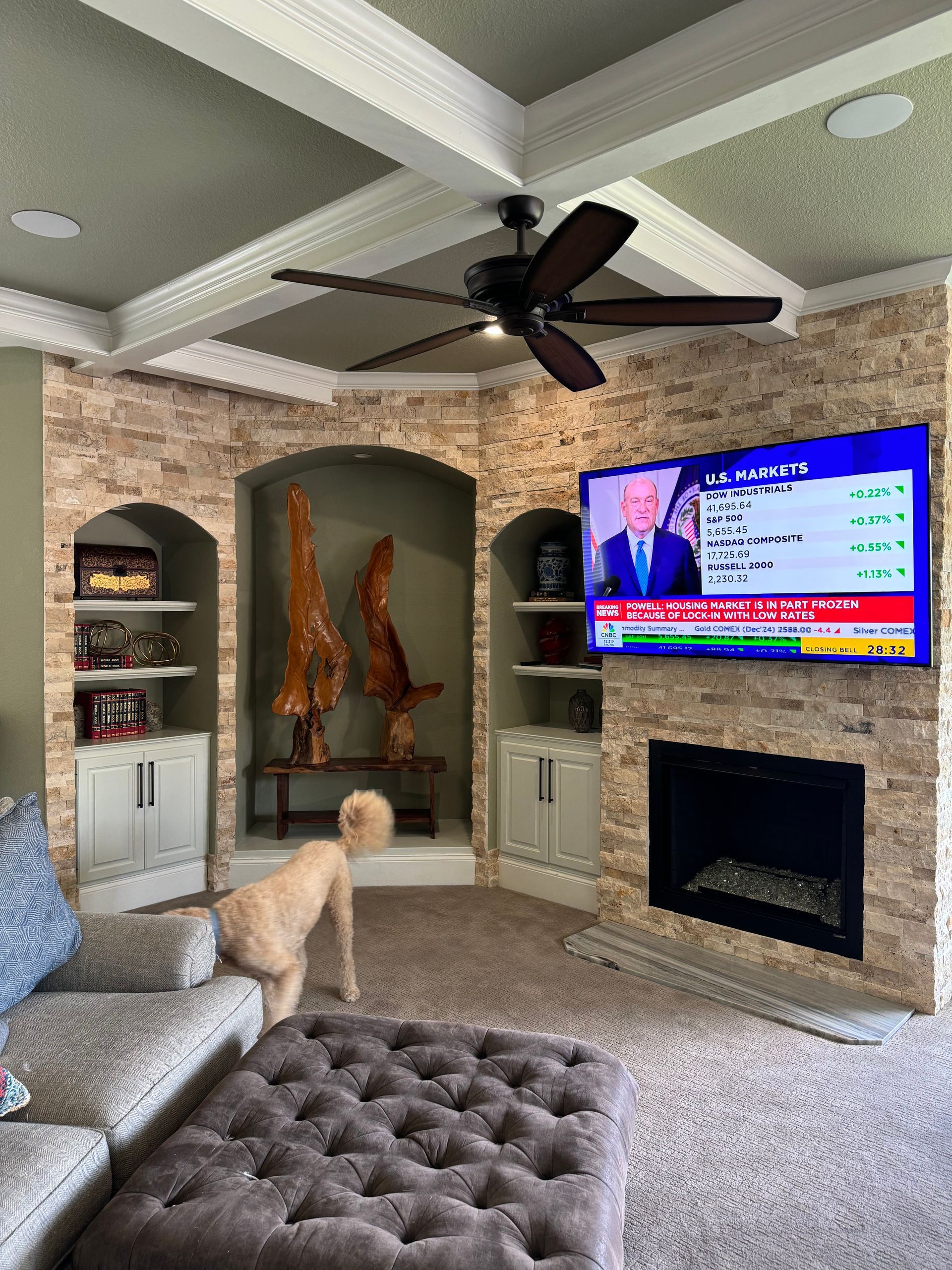 A living room with a couch , ottoman , fireplace and television.