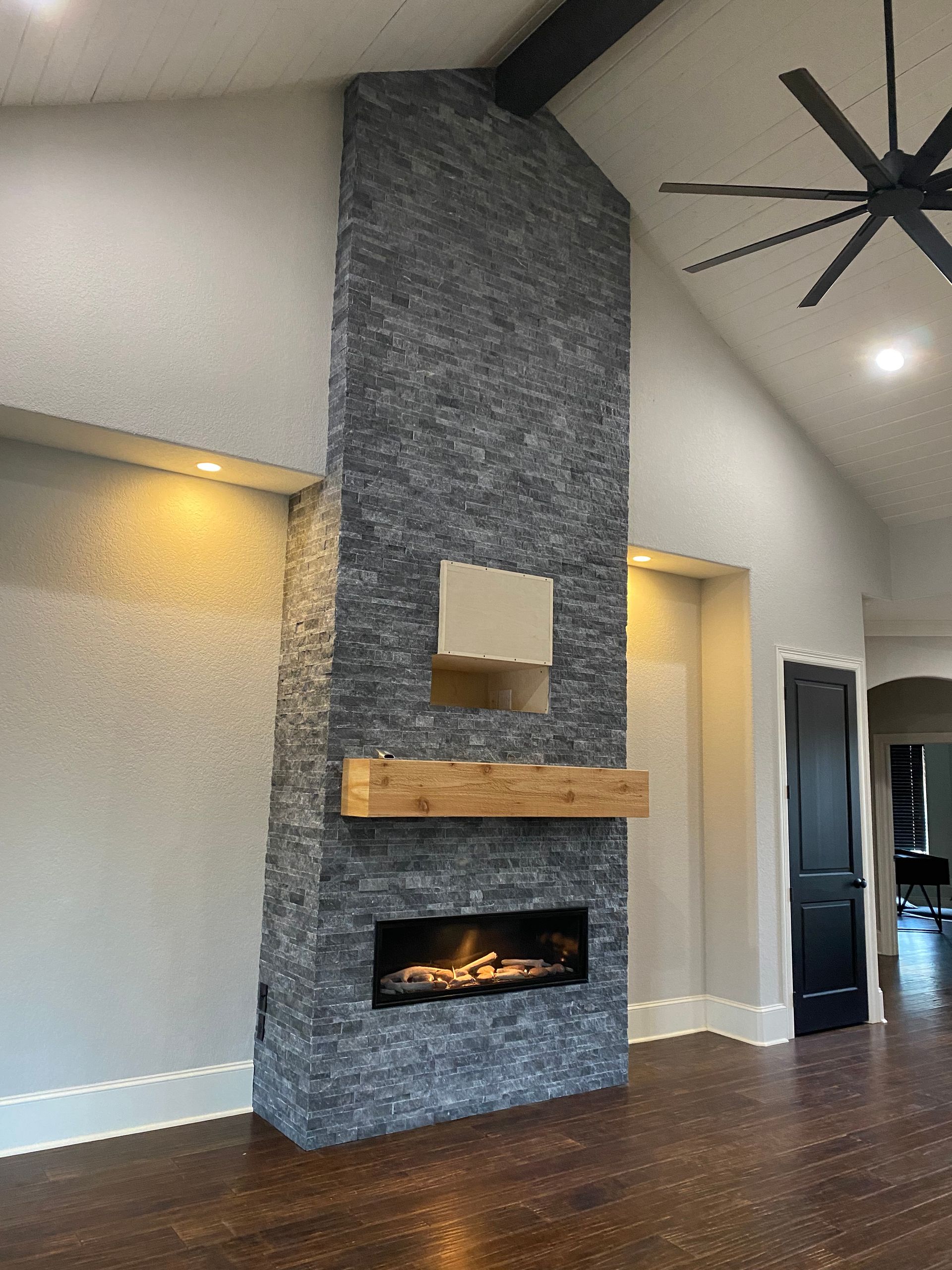A living room with a fireplace and a ceiling fan.