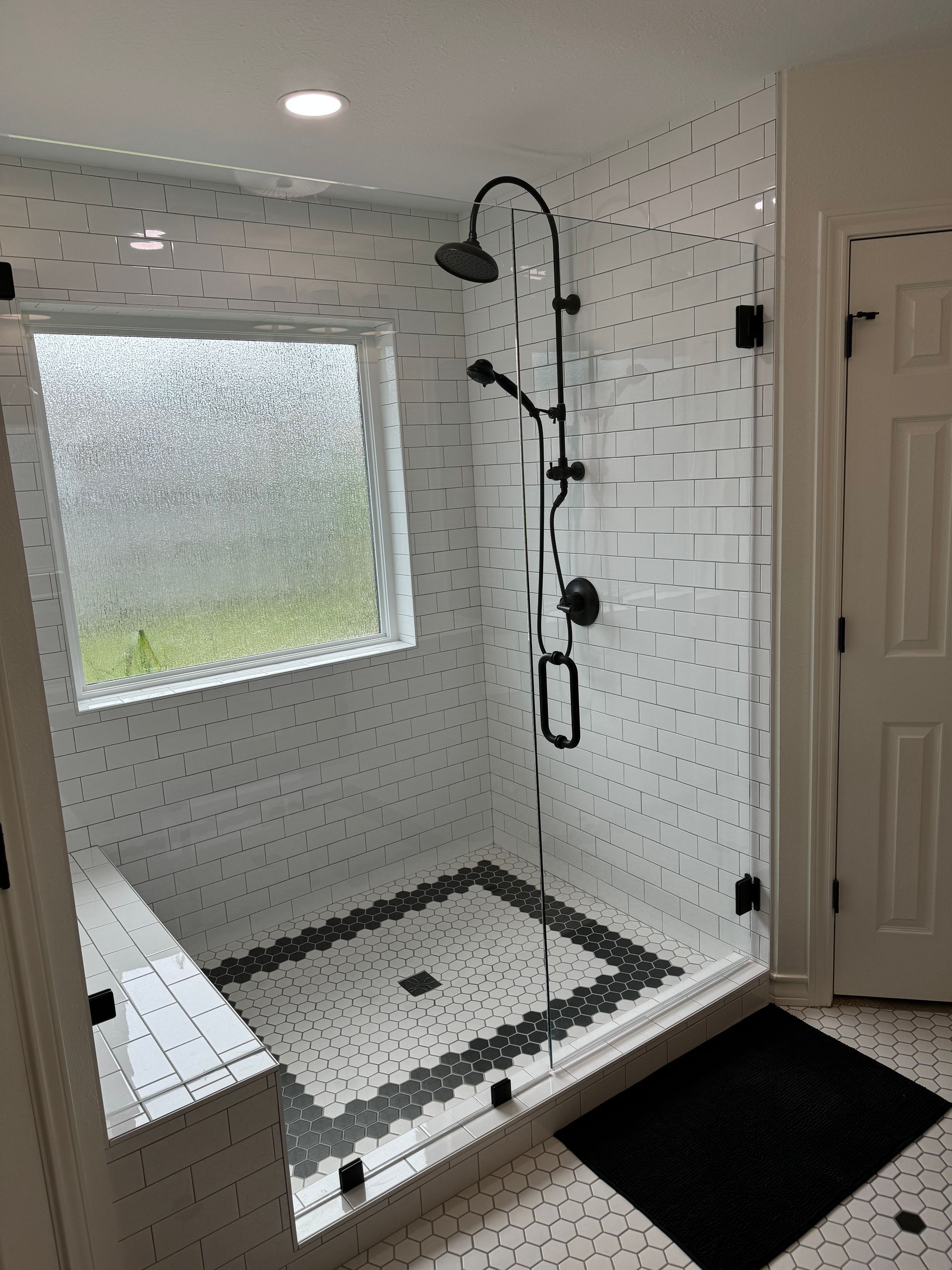 A bathroom with a walk in shower and a window.
