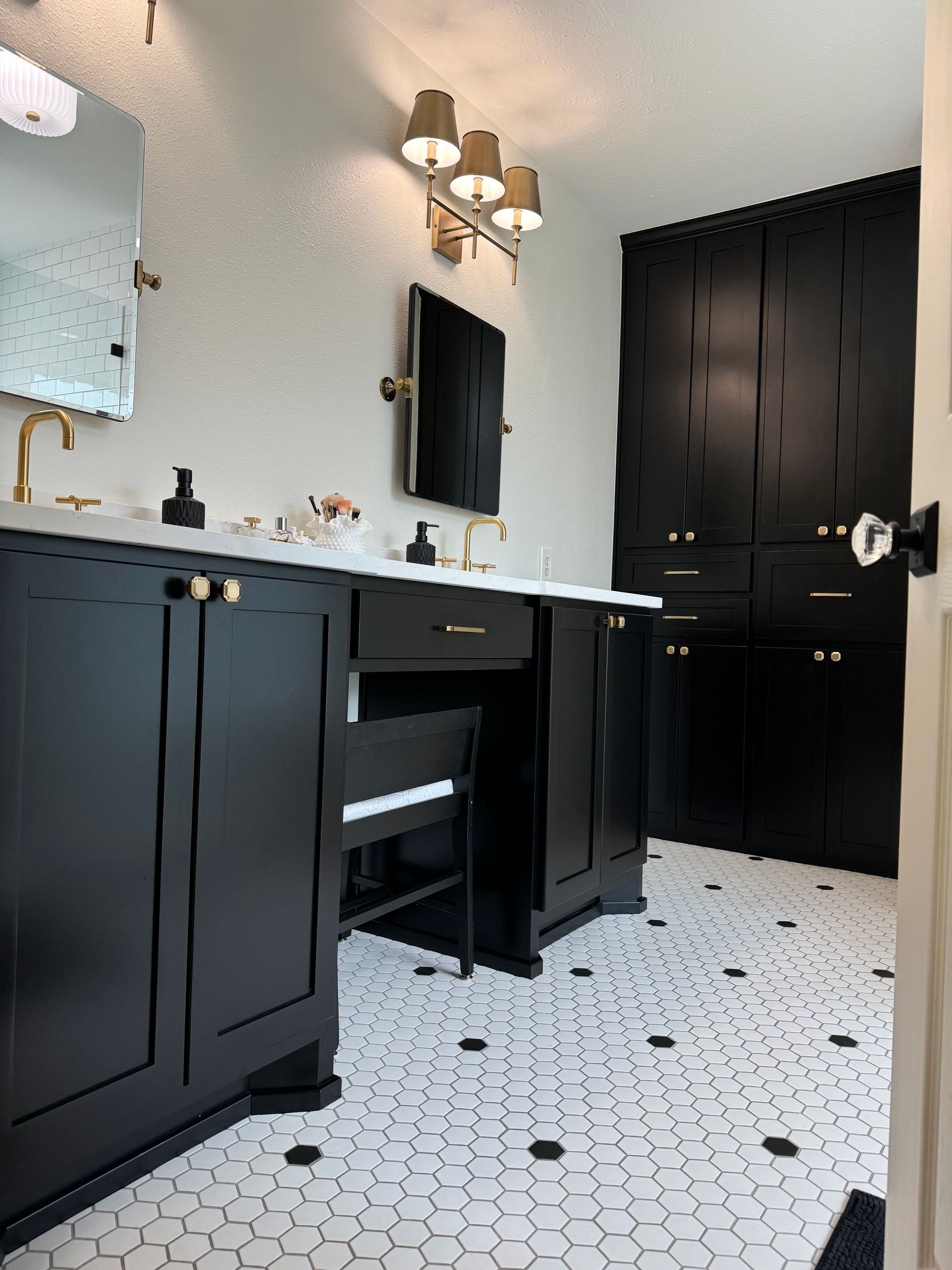 A bathroom with black cabinets and a white tile floor.