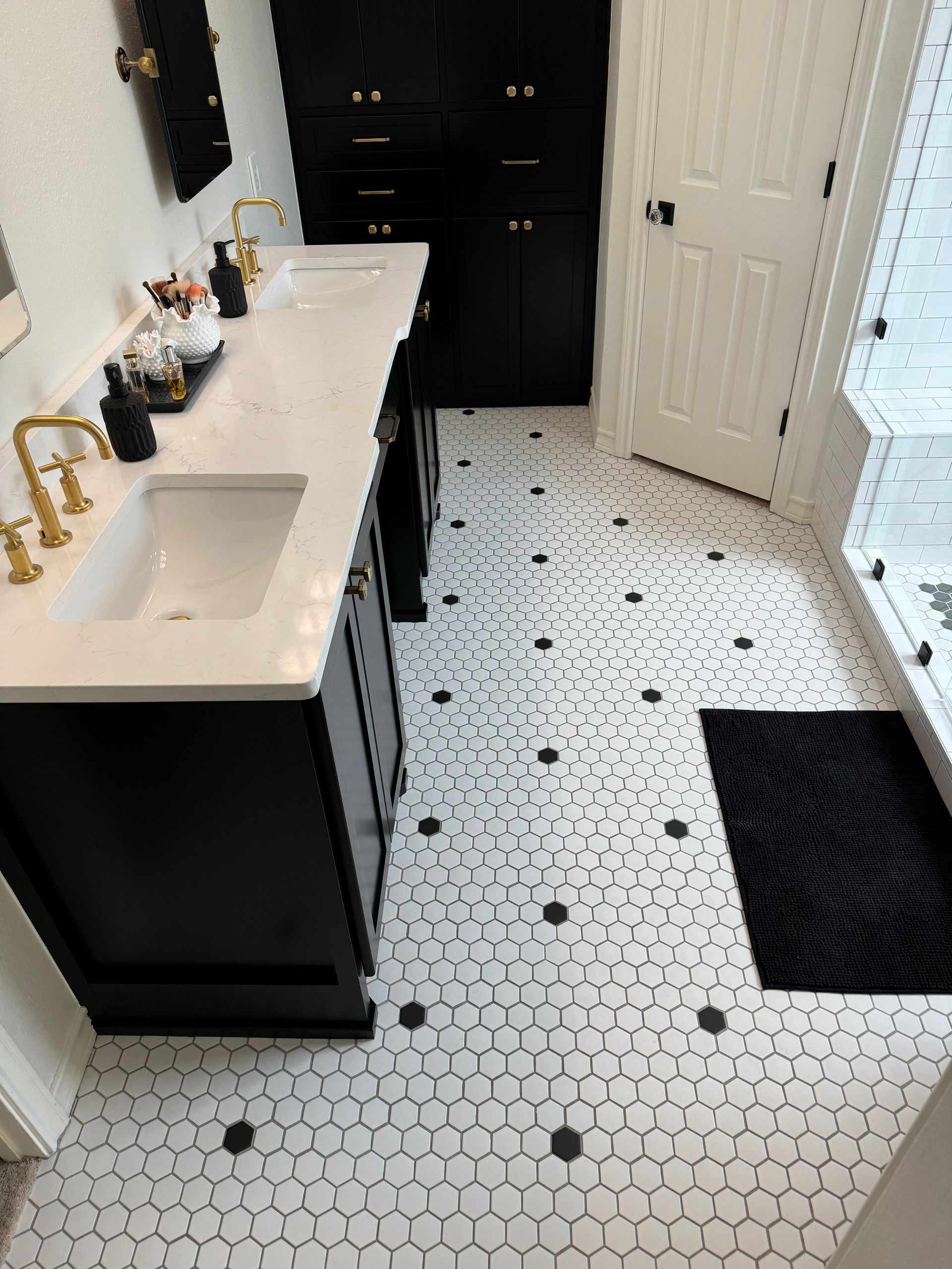 A bathroom with black cabinets and white tile floors.
