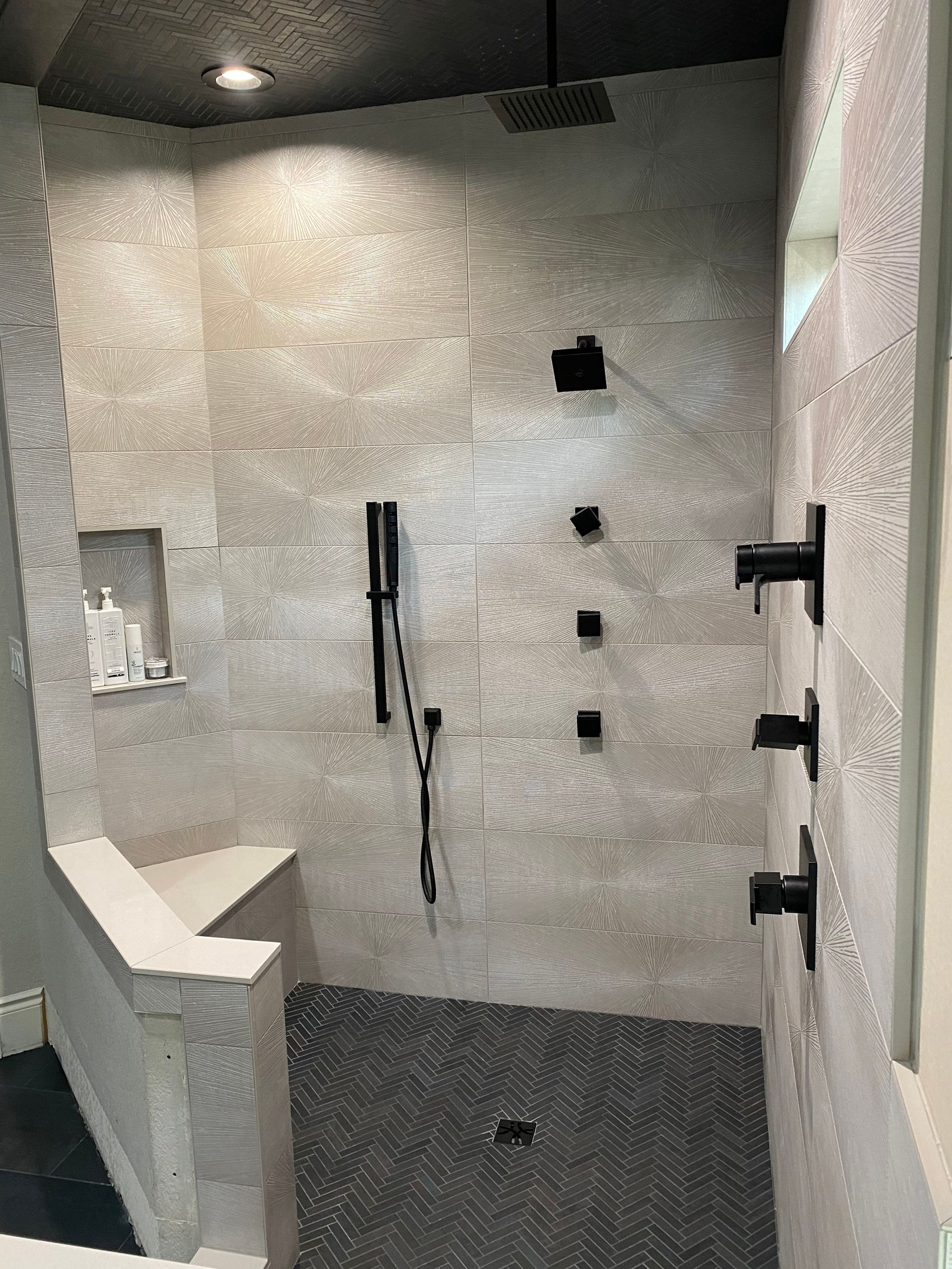 A bathroom with a walk in shower and a bench.