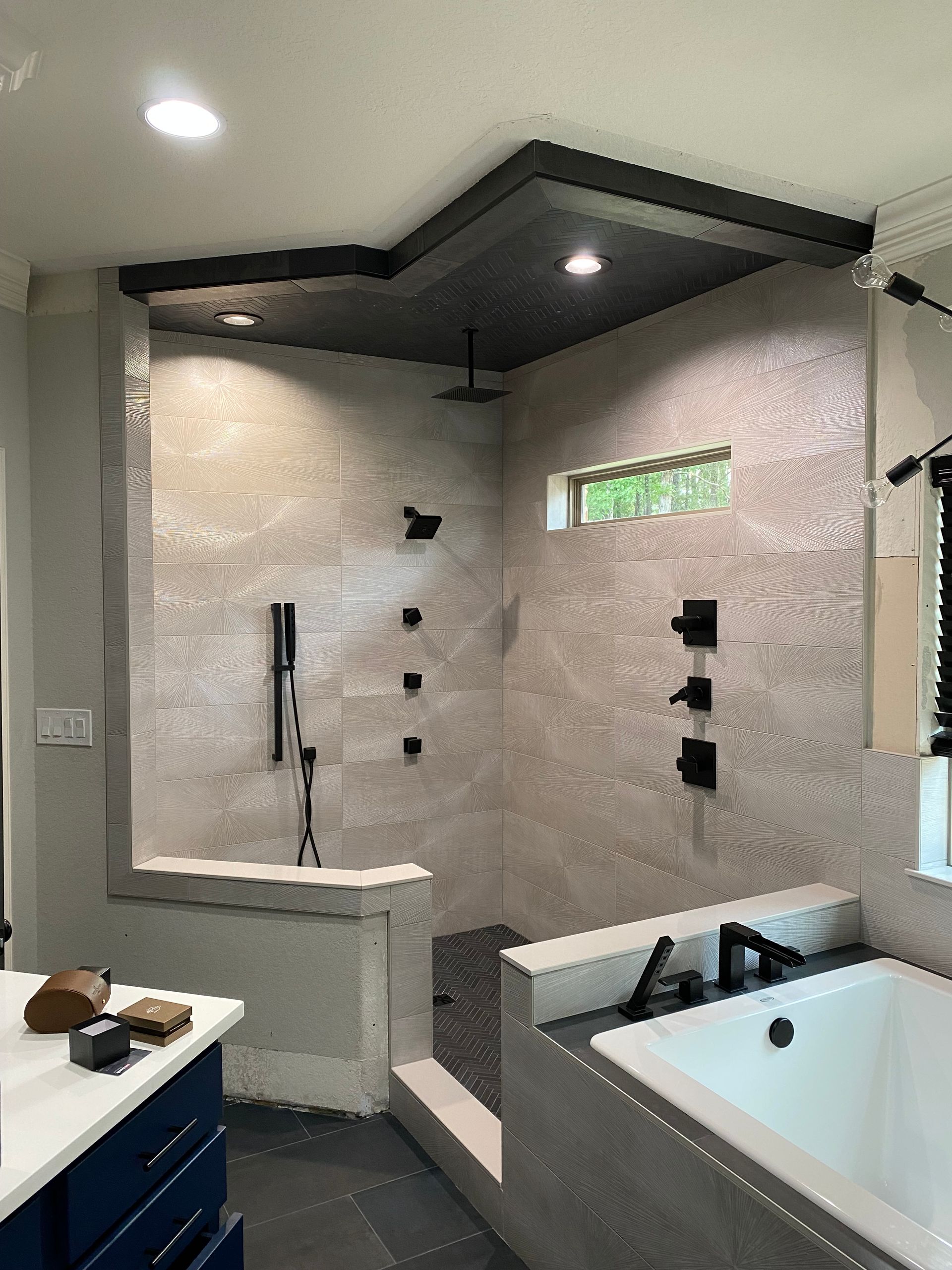 A bathroom with a tub , shower , sink and mirror.