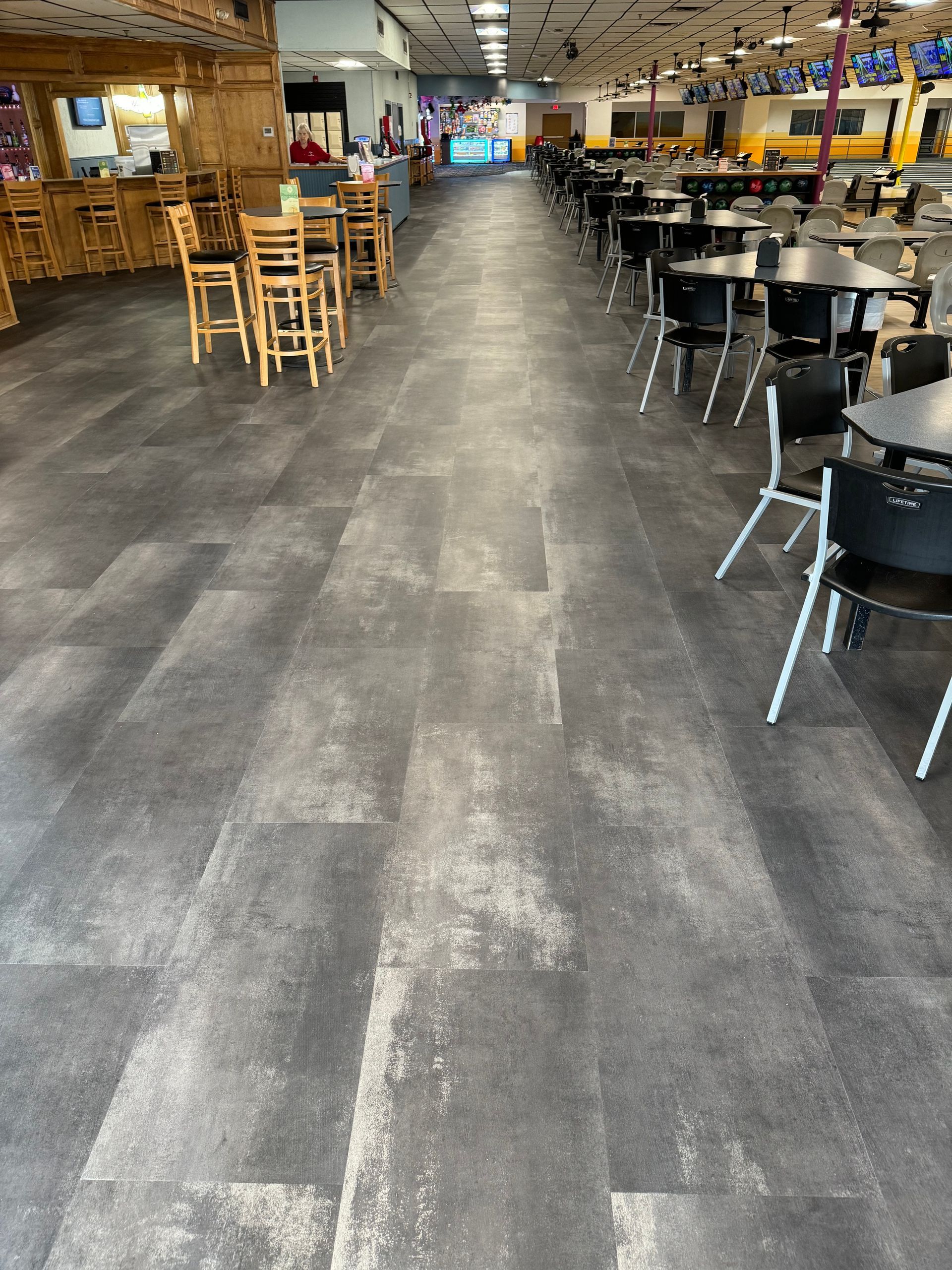 A long hallway with tables and chairs in a restaurant