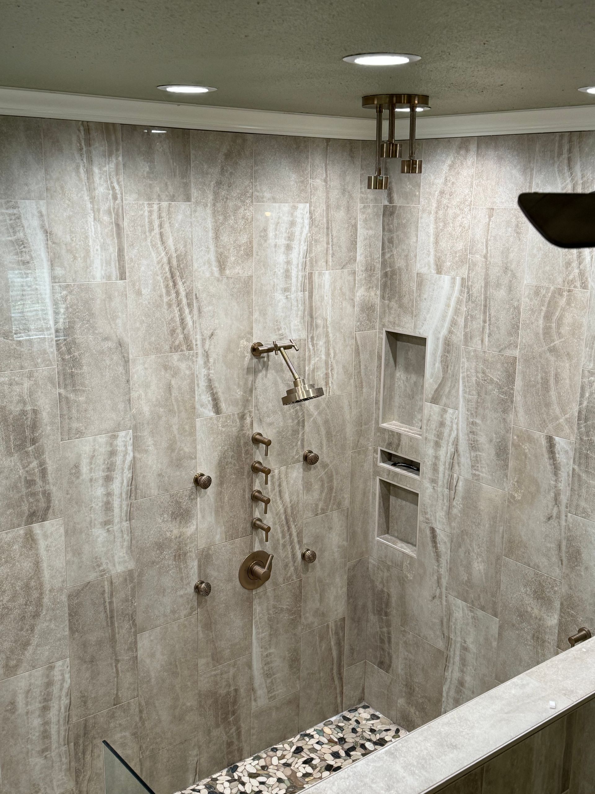 A bathroom with a walk in shower and a ceiling fan.