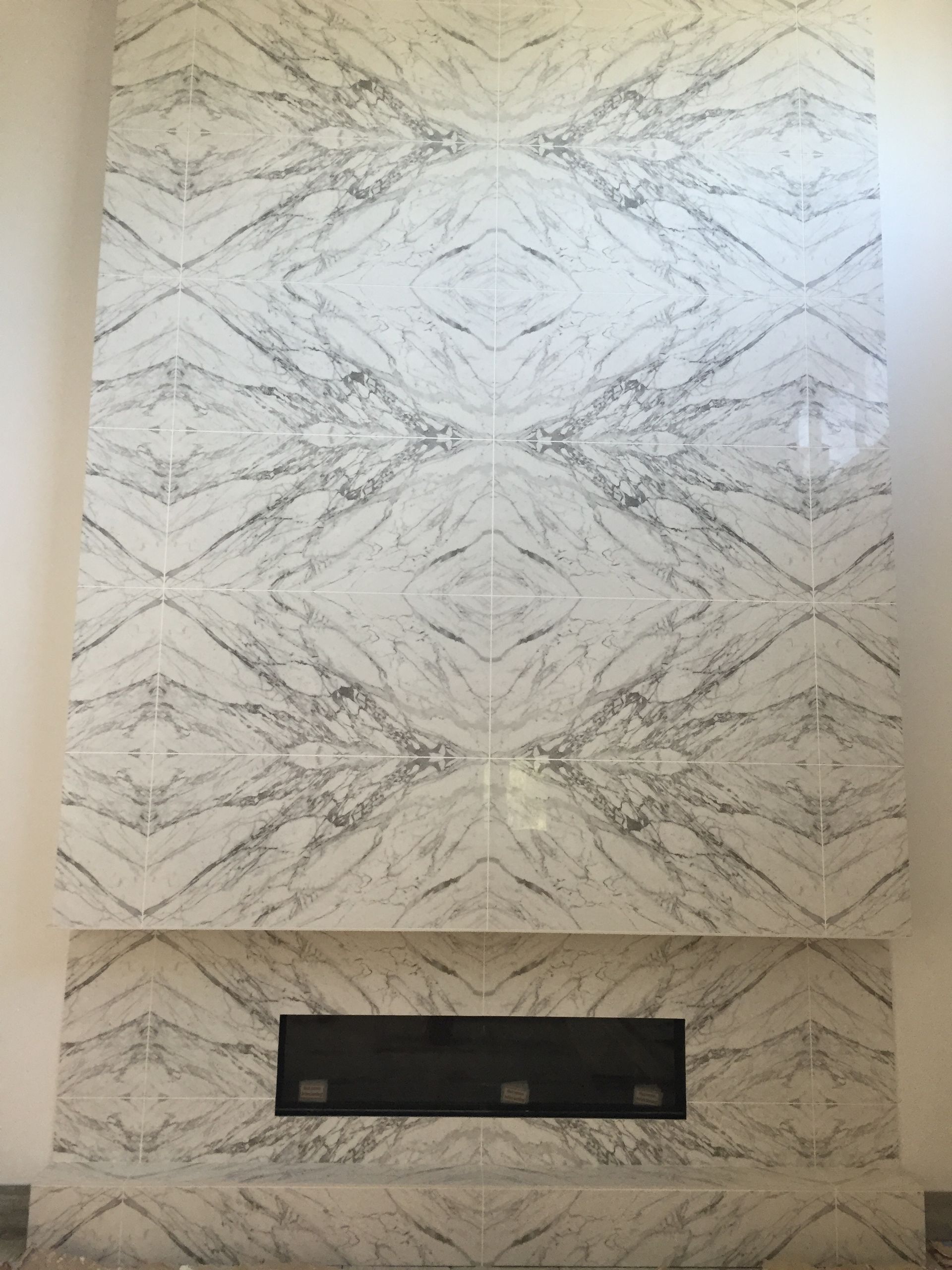 A fireplace with a marble wall behind it