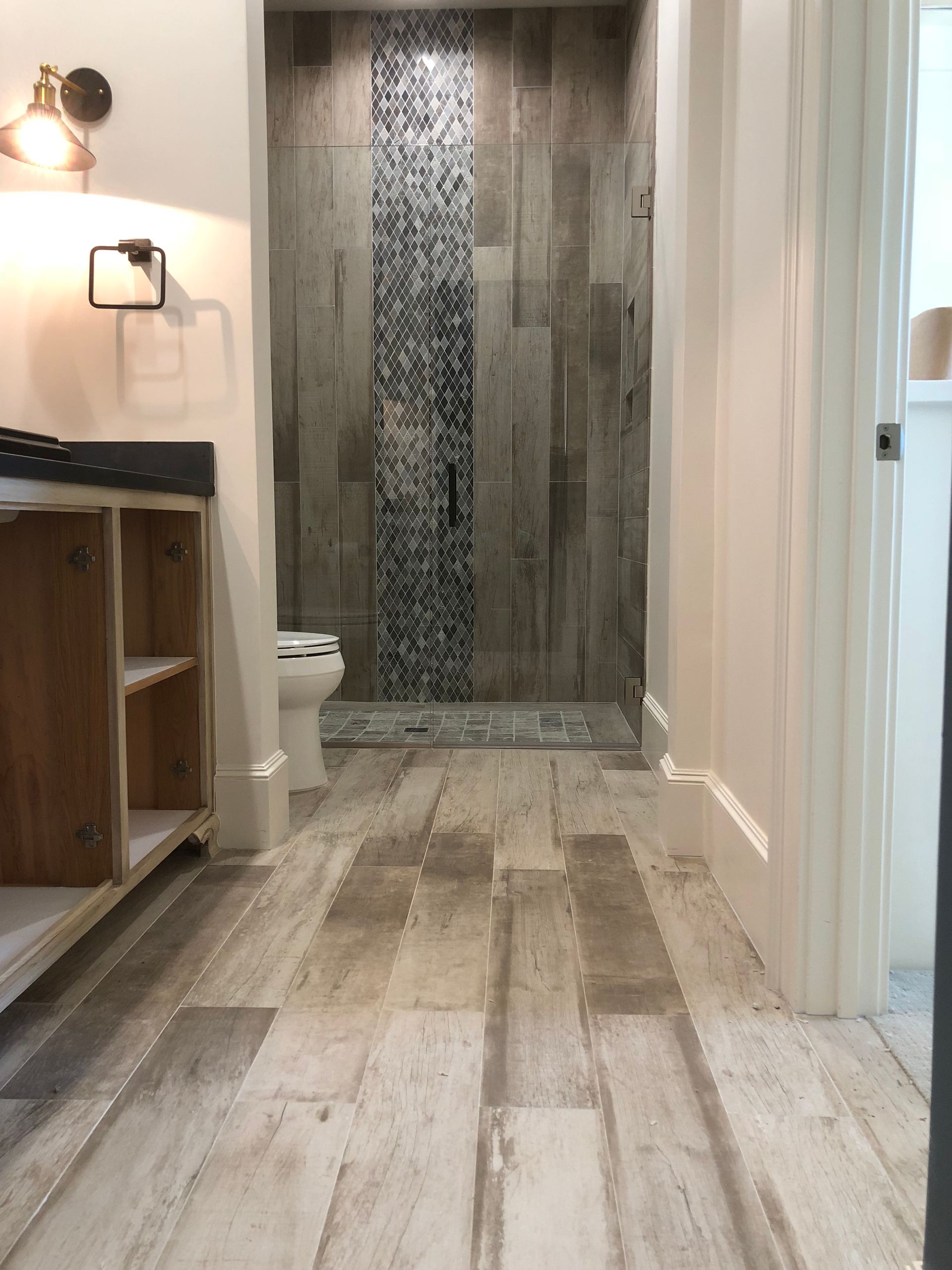 A bathroom with wooden floors and a walk in shower.