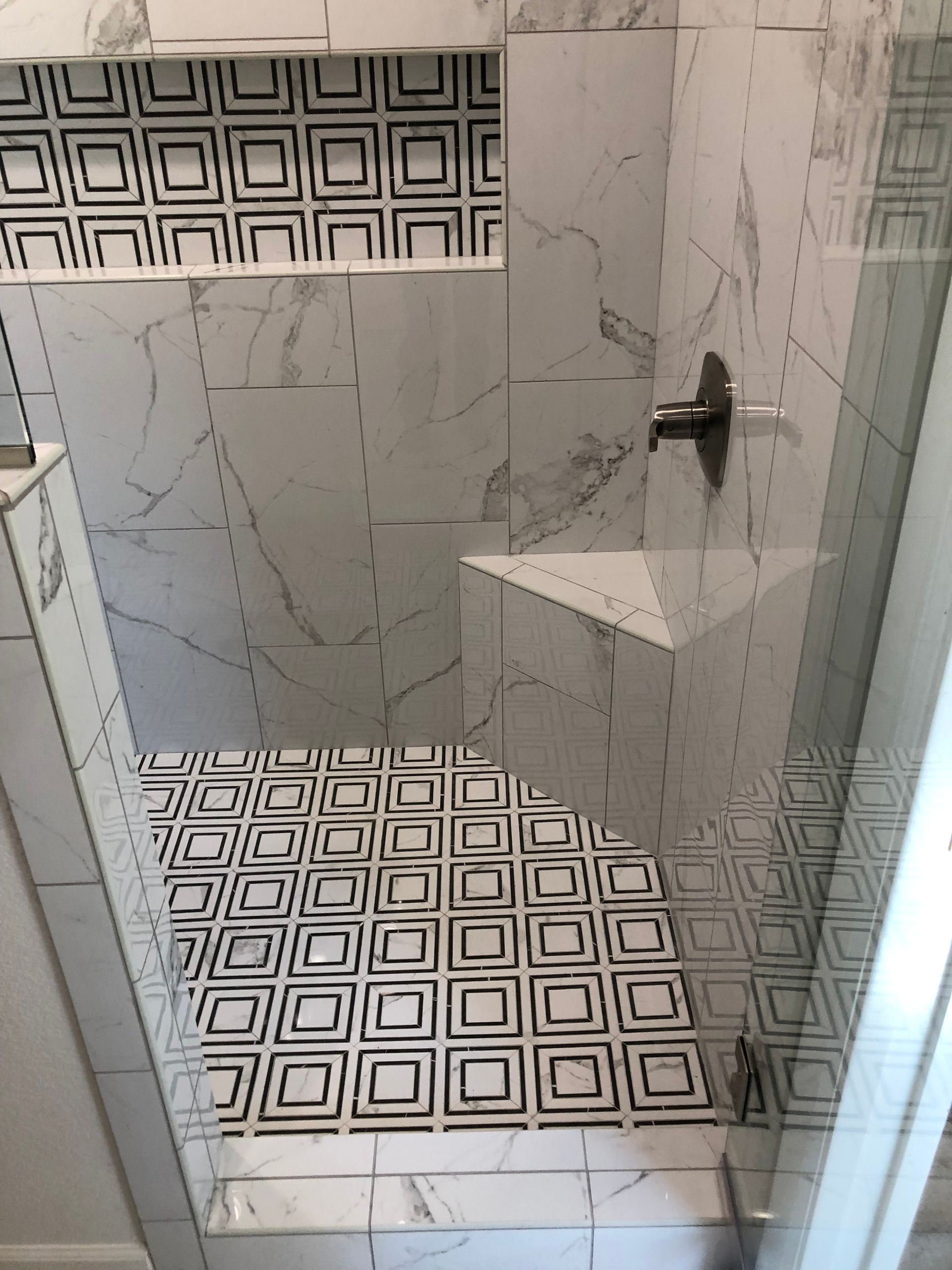 A bathroom with a walk in shower and a black and white tile floor.