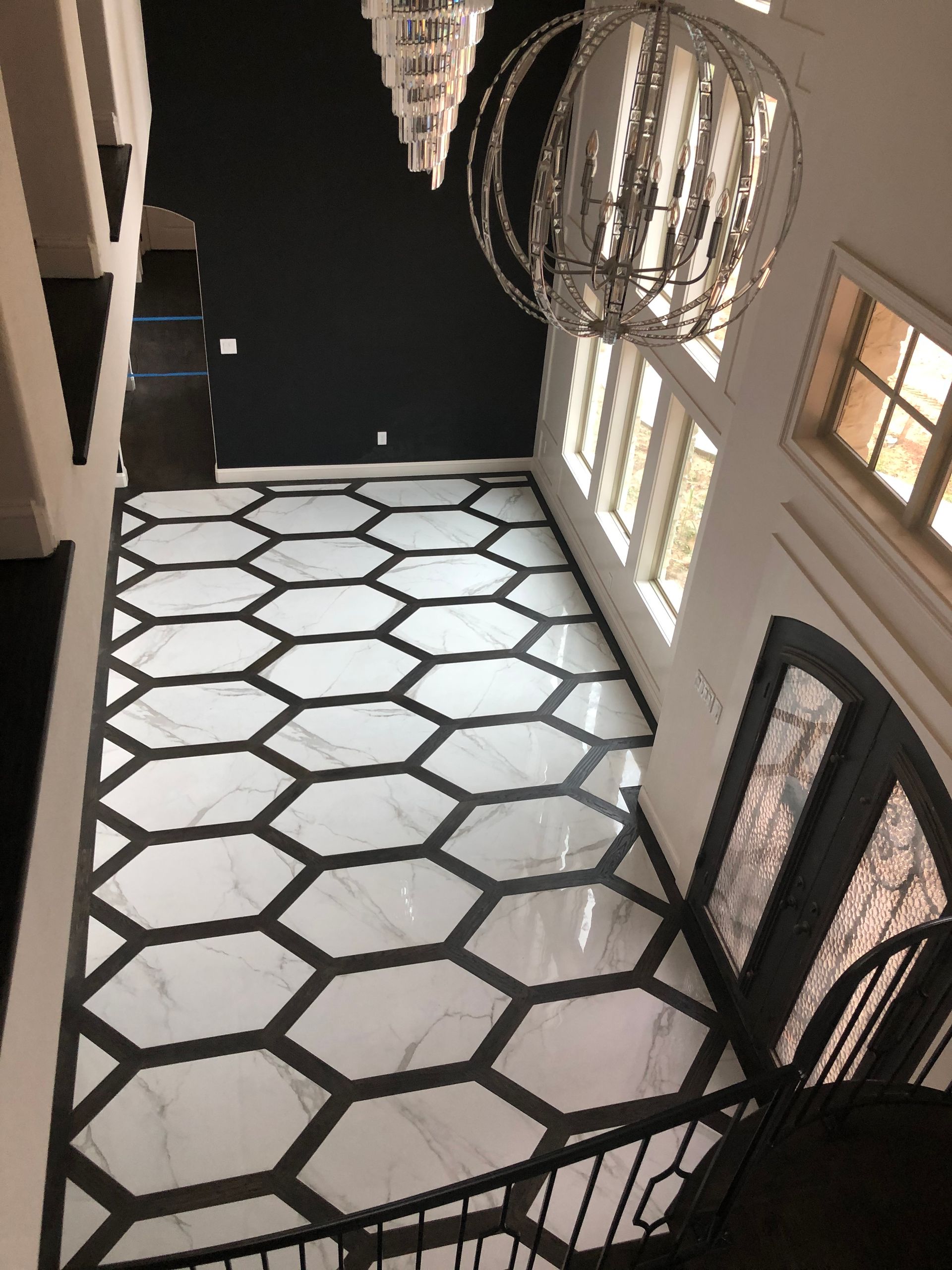 A hallway with a black and white tile floor and a chandelier hanging from the ceiling.