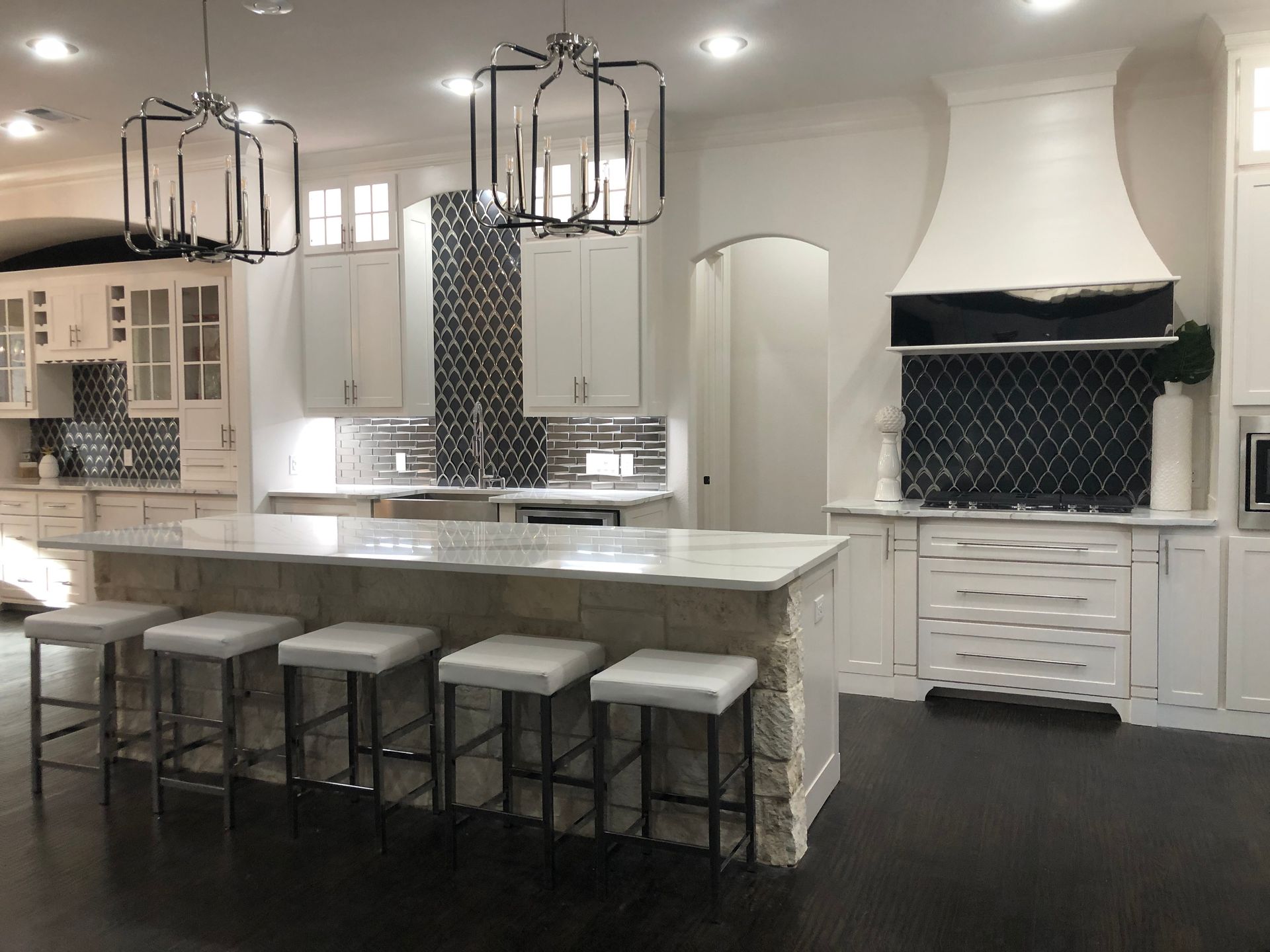 A kitchen with white cabinets and stools and a large island
