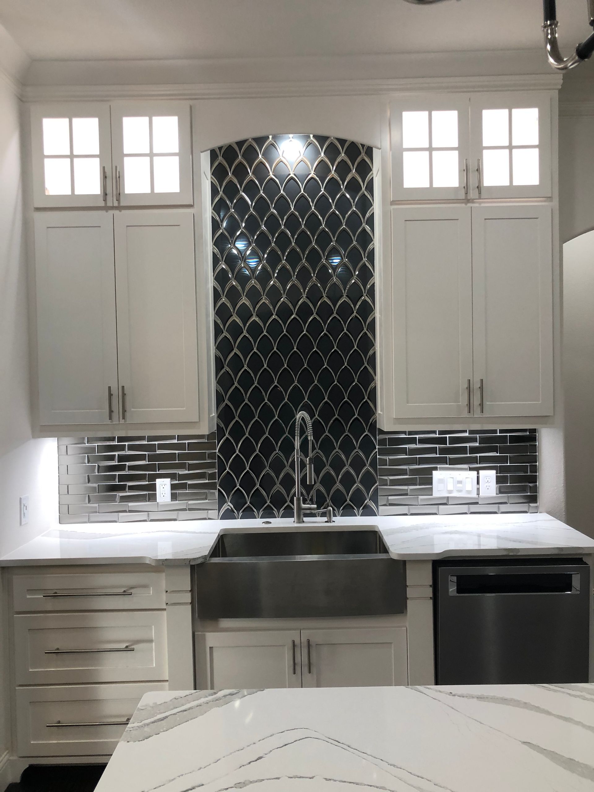 A kitchen with white cabinets and a stainless steel sink