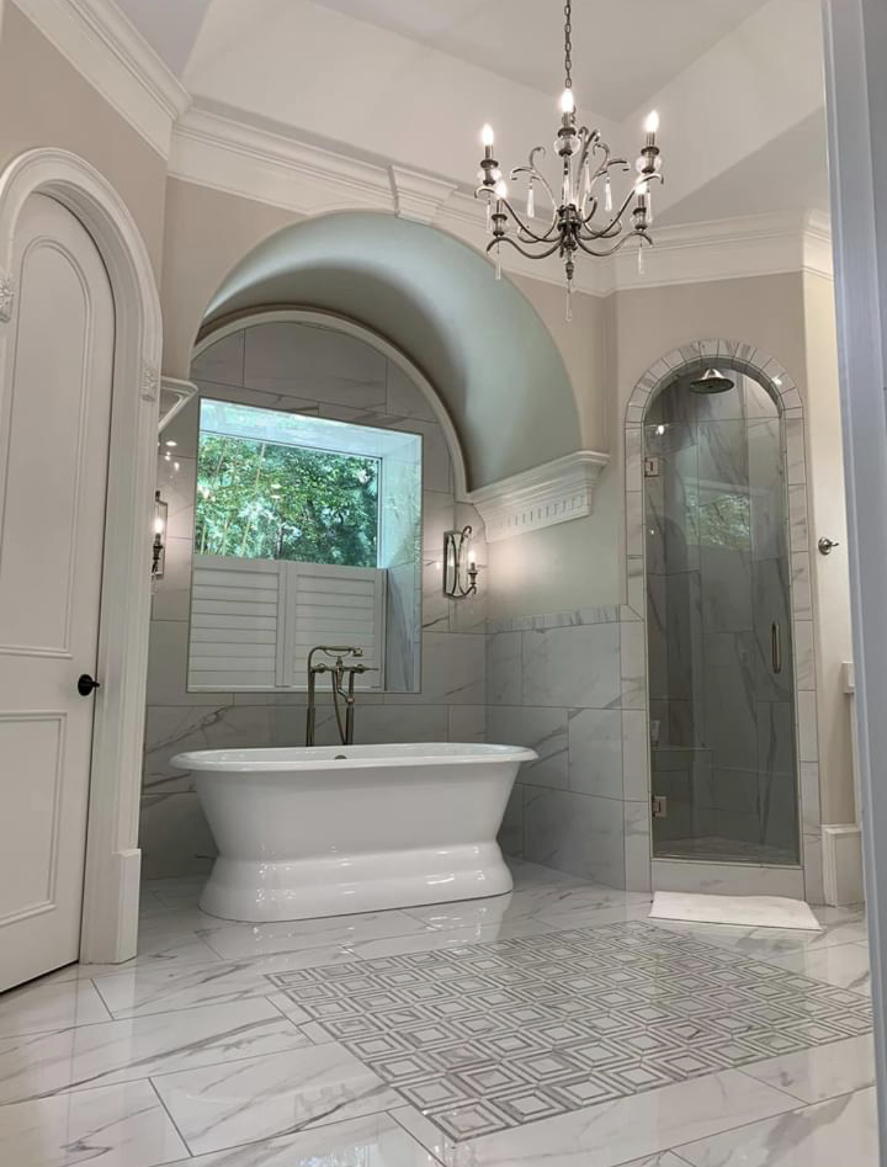 A bathroom with a bathtub , shower , and chandelier.