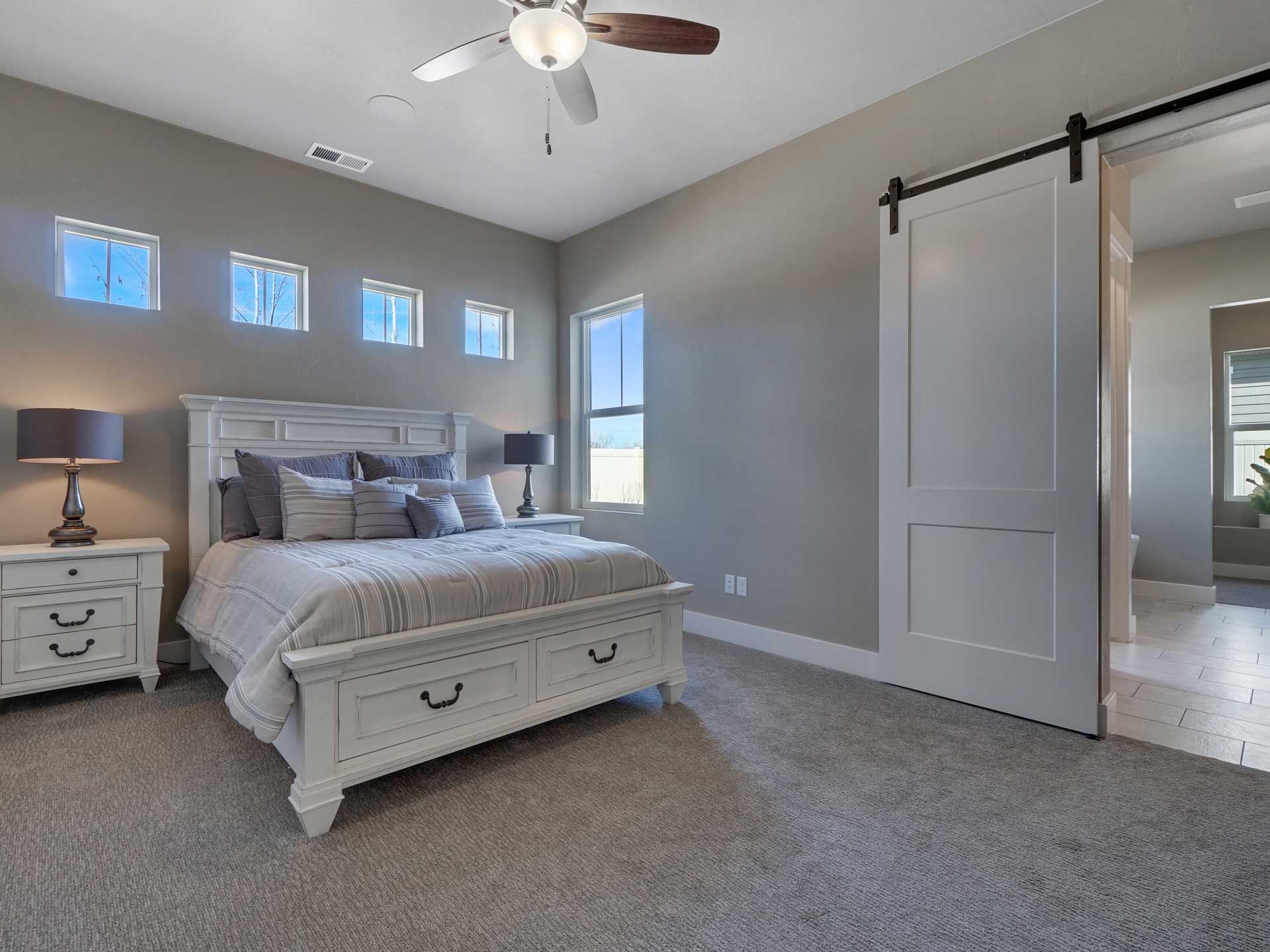 A bedroom with a bed , nightstands , lamps and a ceiling fan.