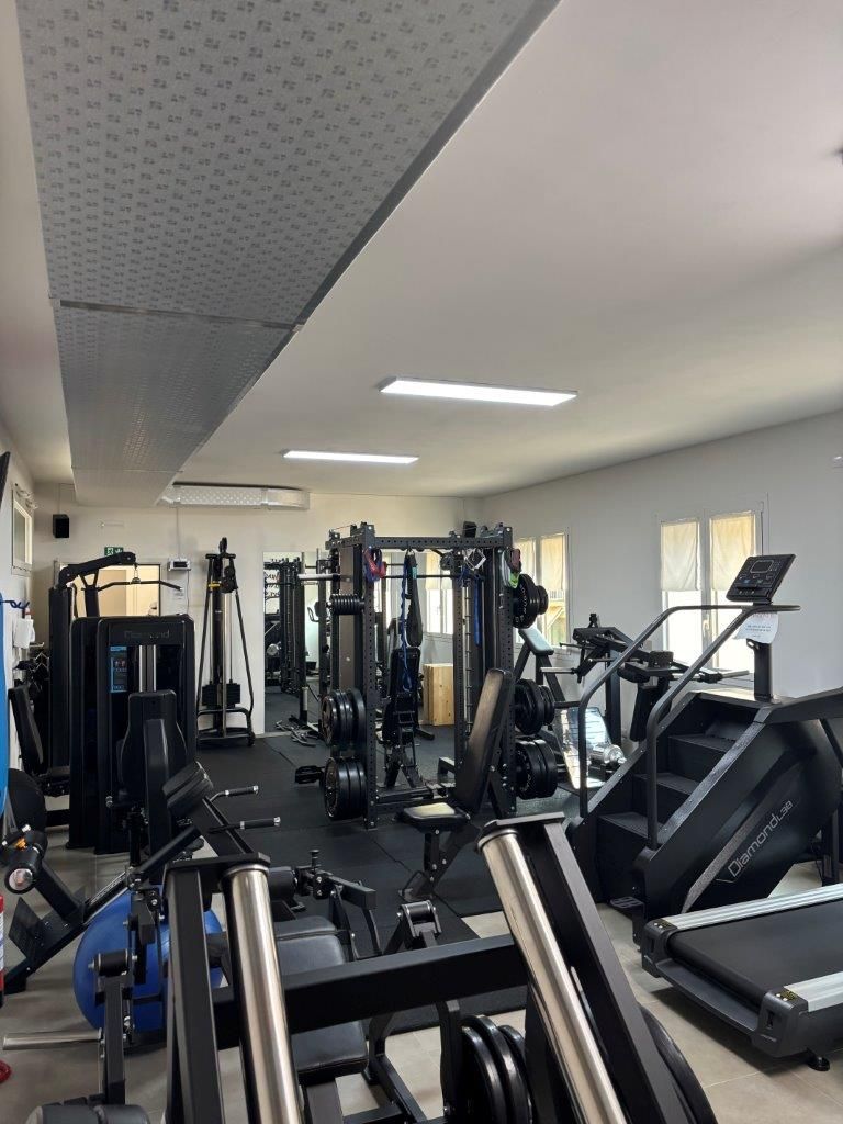 Interno dello studio NVGYM con vari attrezzi ginnici in una stanza ben illuminata. Tra i macchinari figurano tapis roulant, stepper e attrezzi per l'allenamento con i pesi.