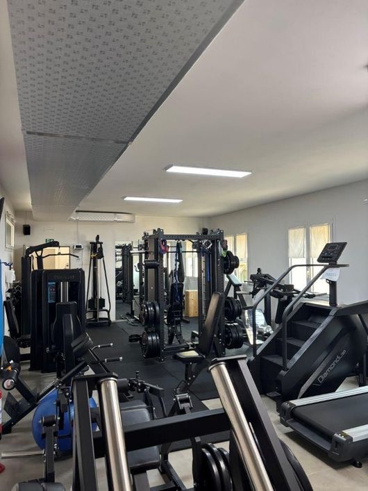 Interno dello studio NVGYM con vari attrezzi ginnici in una stanza ben illuminata. Tra i macchinari figurano tapis roulant, stepper e attrezzi per l'allenamento con i pesi.