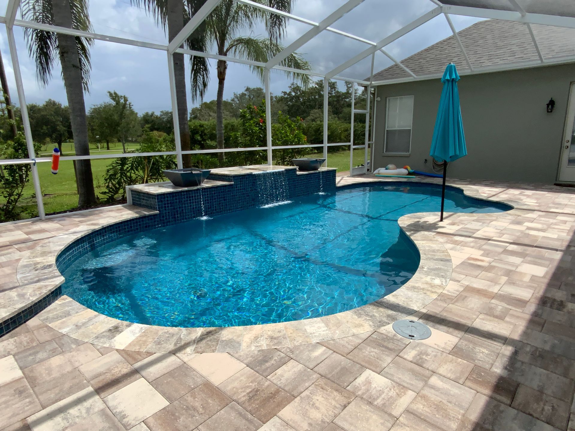 Pool with blue tiles, life preserver, and green grass border.