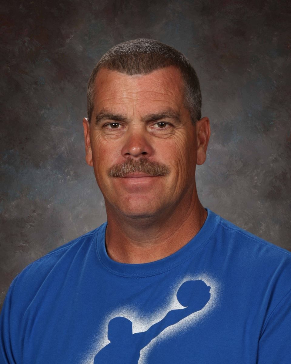 A man with a mustache is wearing a grey shirt and posing for a picture.