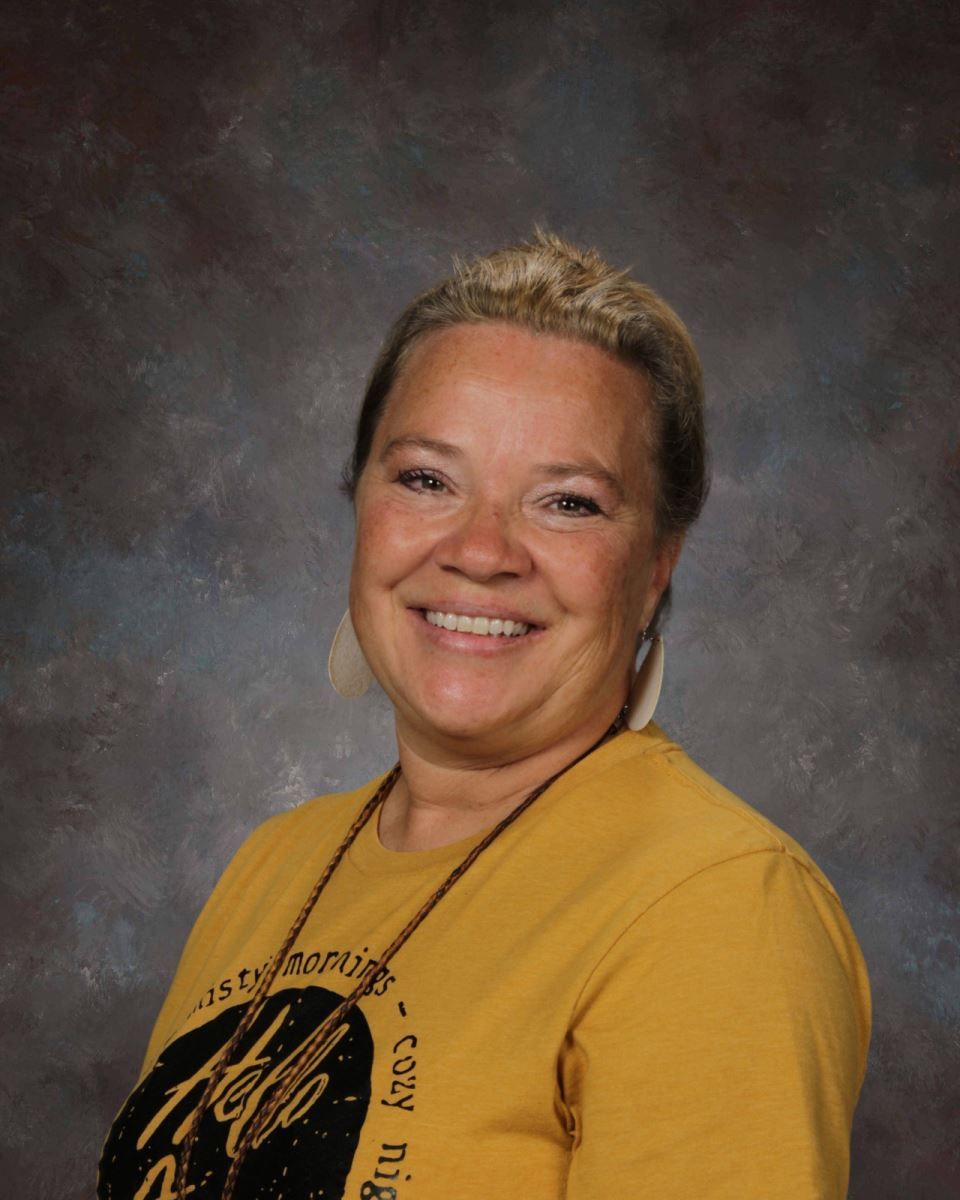A woman in a yellow shirt is smiling for the camera.