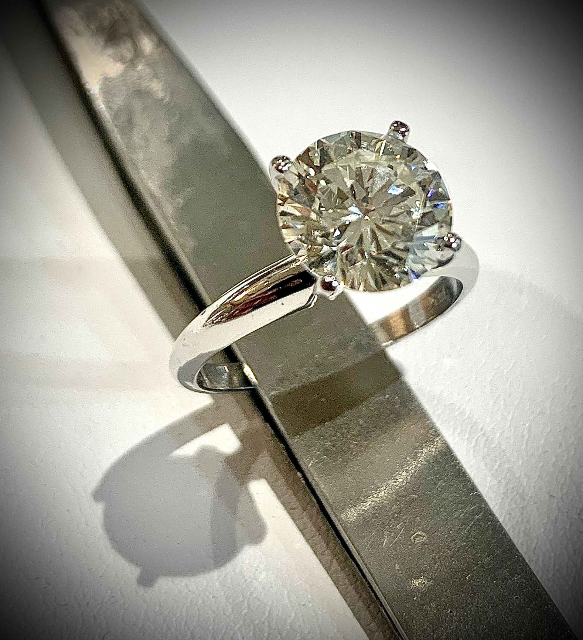A diamond ring is sitting on top of a metal bar.