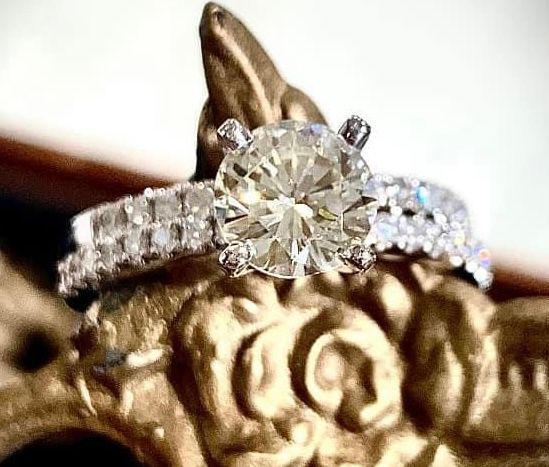 A diamond ring is sitting on top of a gold object.