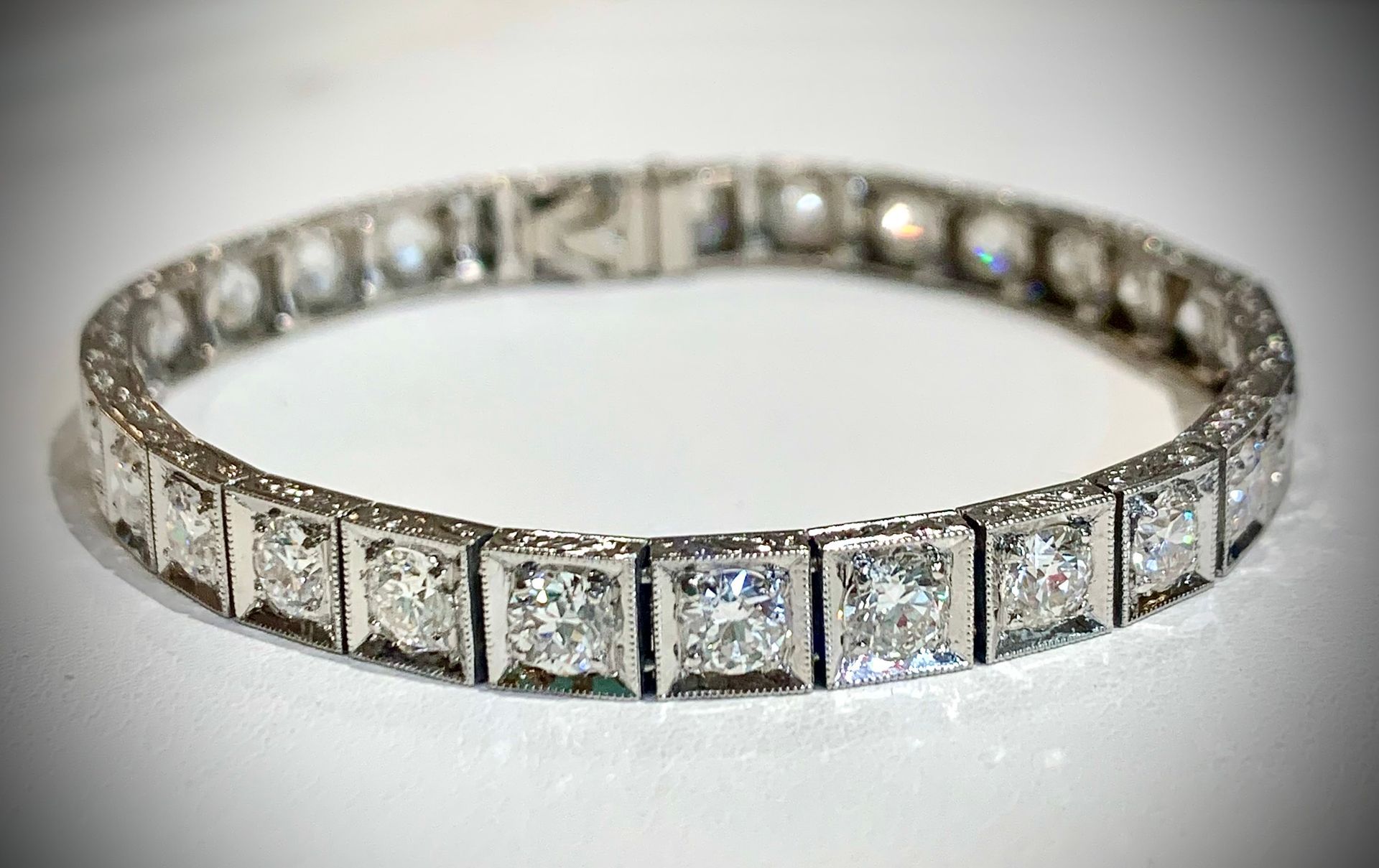 A close up of a diamond bracelet on a white surface.