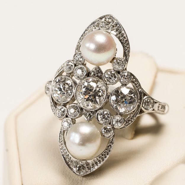 A ring with pearls and diamonds on a white surface