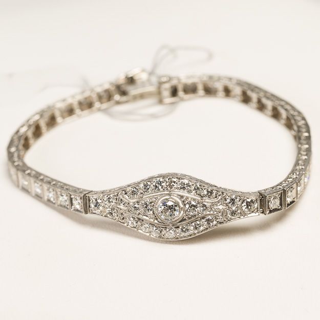 A close up of a diamond bracelet on a white surface