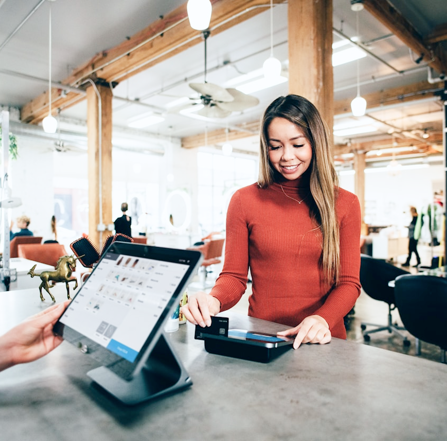 Woman paying with credit card at a shop counter with a smiling expression.
