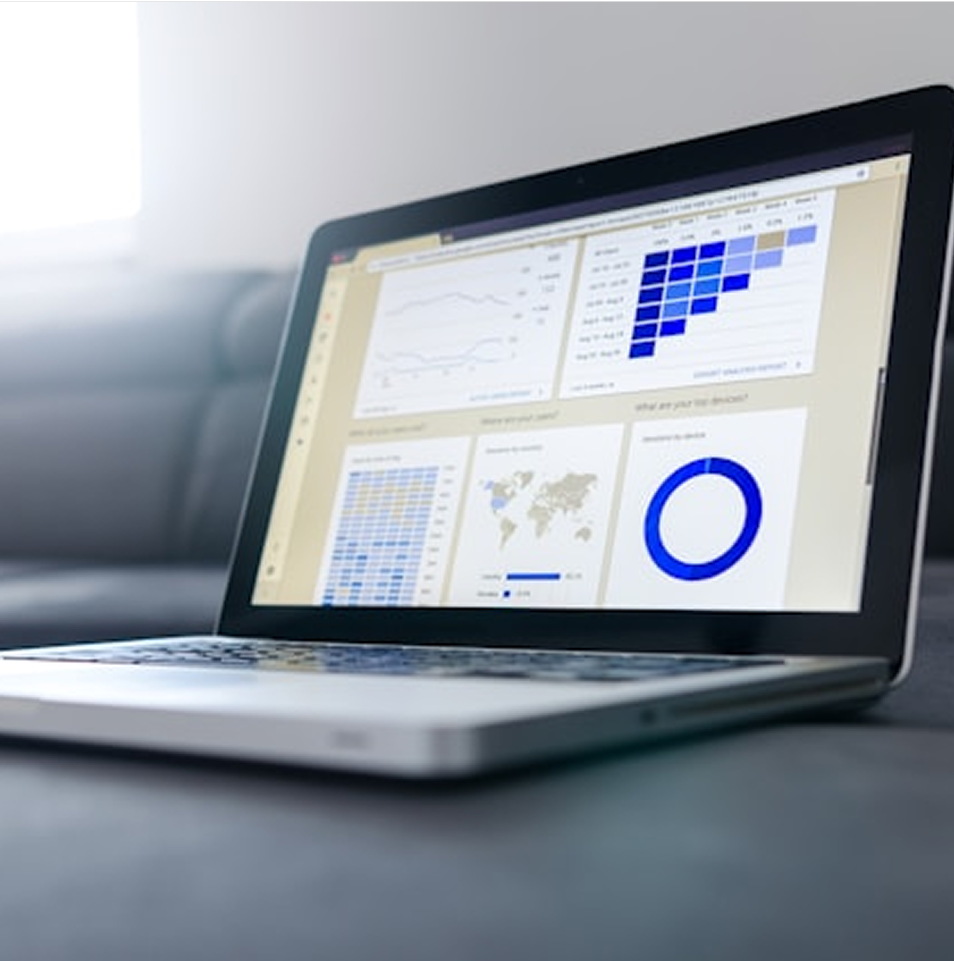 Laptop displaying data visualizations, charts, and graphs on a gray surface.