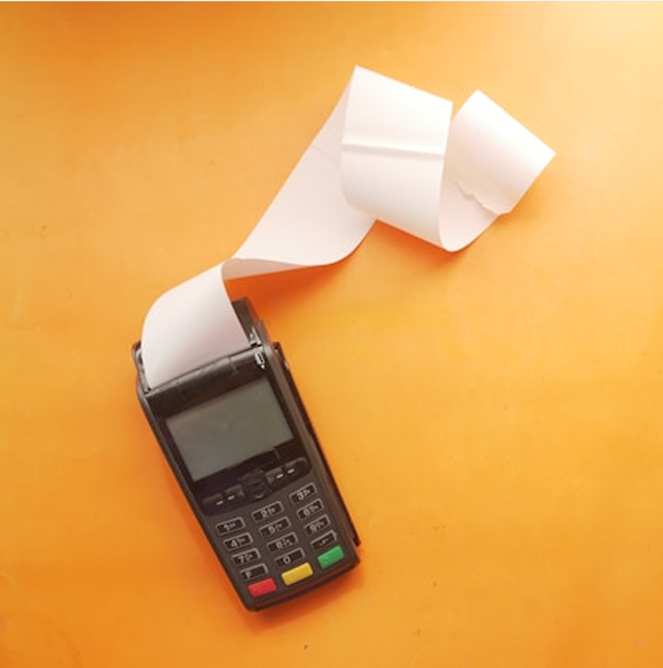 Payment terminal with receipt on orange background.