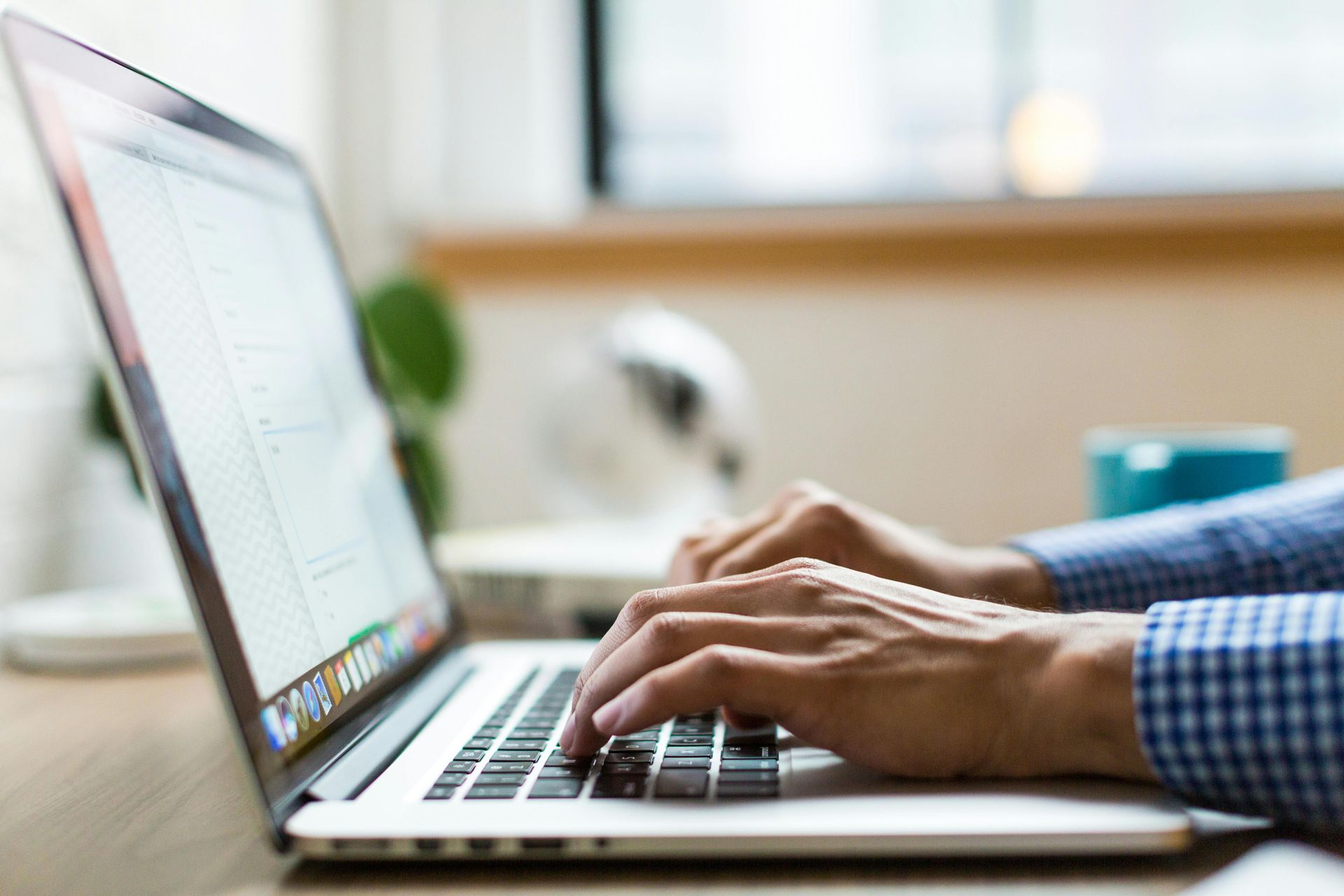 Person typing on a laptop at a desk, with hands in focus.