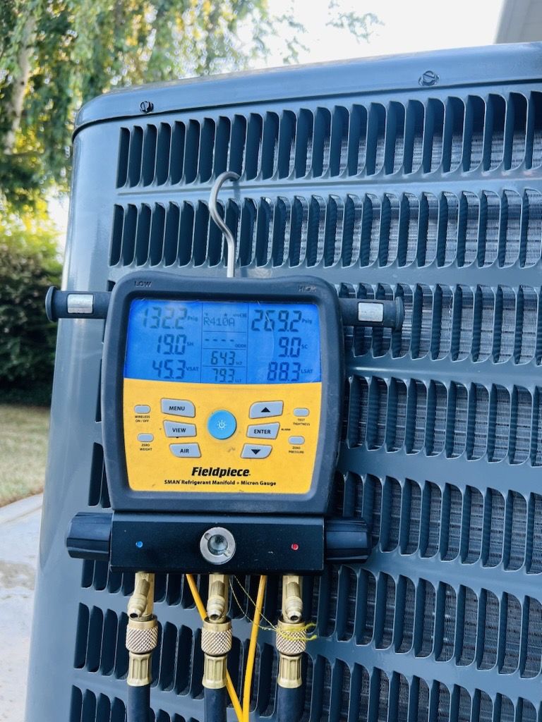 A digital thermometer is attached to the back of an air conditioner.