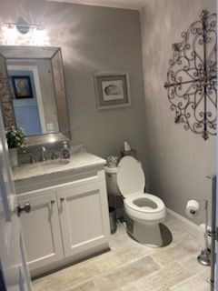 A bathroom with a toilet , sink and mirror.