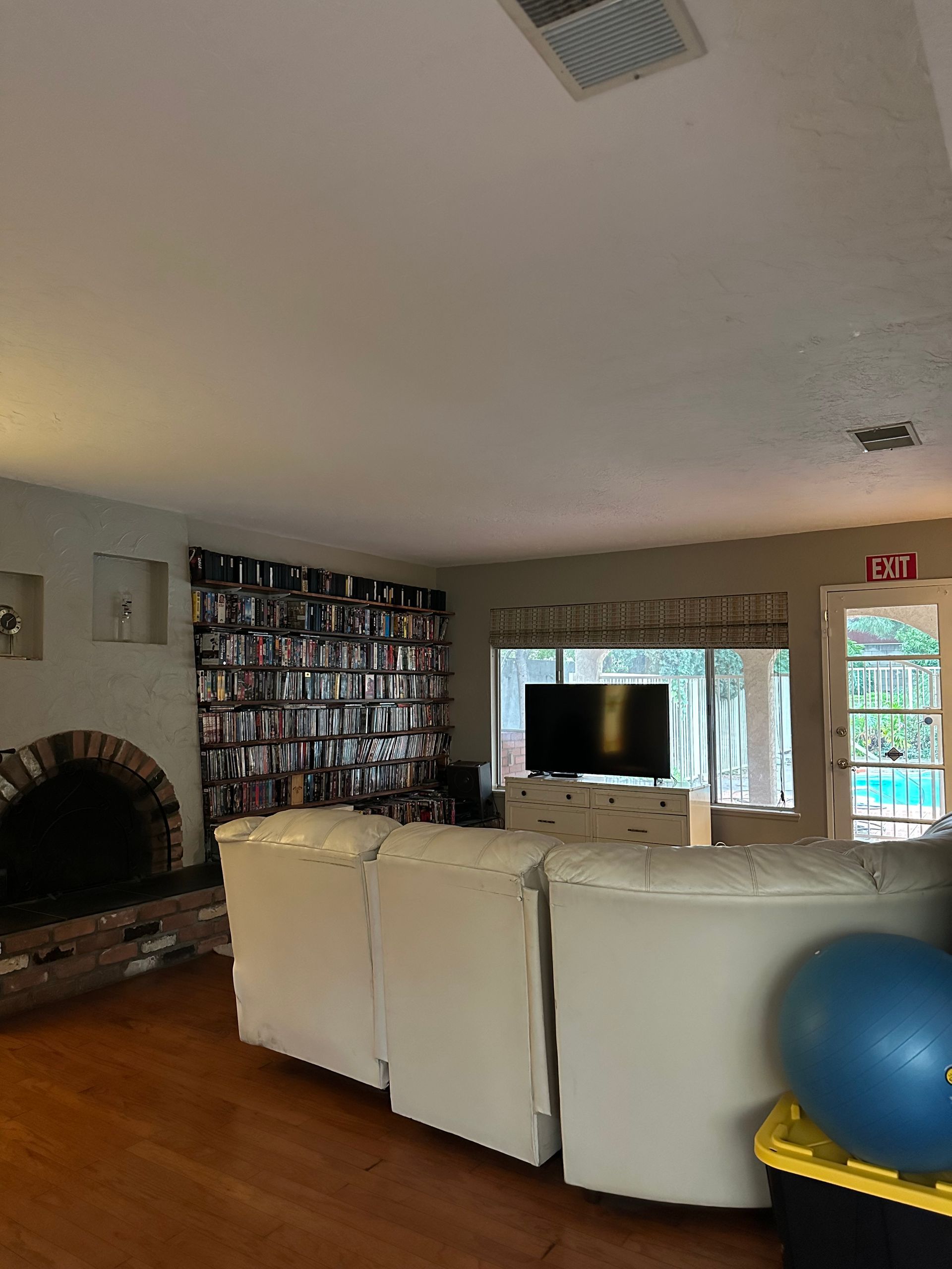 Living room with white couch, fireplace, TV, and large bookshelf wall.