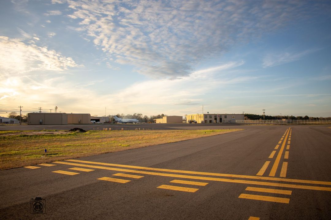 Empty runway with yellow markings under a blue, cloudy sky at sunset