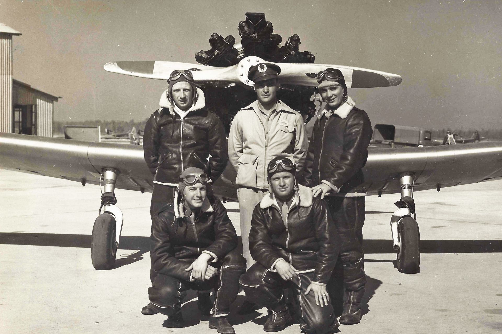 A white and black private jet parked on an airfield with ground crew nearby in a utility vehicle and on foot.
