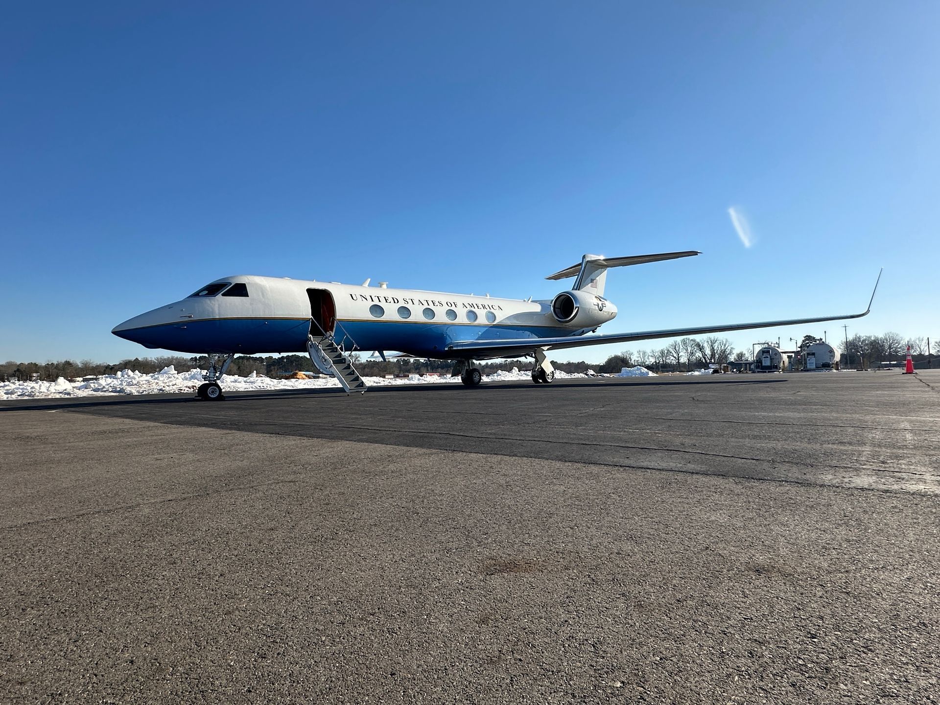 Small private jet parked on a runway under a clear blue sky