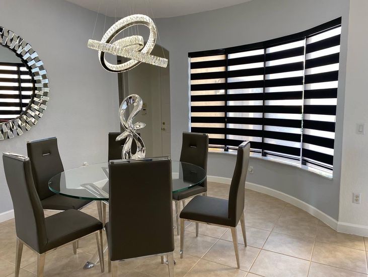 A room with a lot of black and white blinds on the windows.