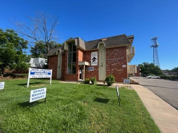 Red brick office building with signs for rental services on a sunny day.