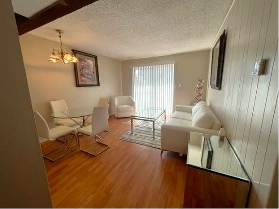 Living room with hardwood floors, white furniture, and a sliding glass door.